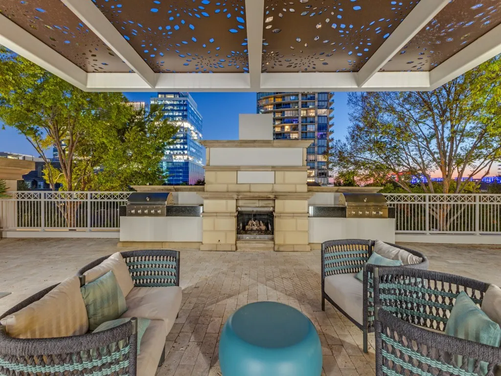Expansive outdoor terrace featuring a built-in fireplace, two integrated grills, and a decorative perforated ceiling