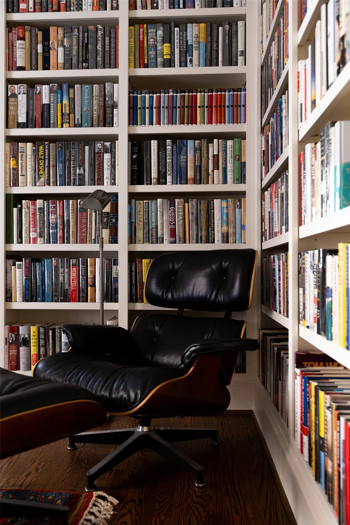 Floor-to-ceiling custom built-in wooden shelving featuring adjustable cabinetry and dark wood-finish flooring