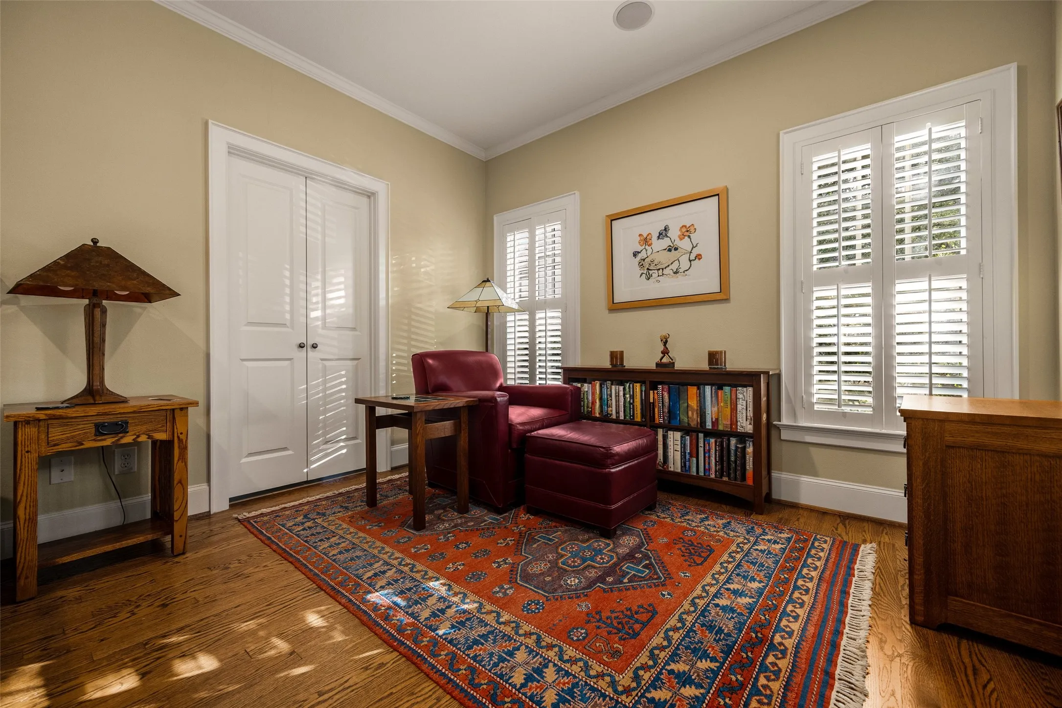 Room featuring wood-finish flooring, white plantation shutters, and dual-panel interior doors