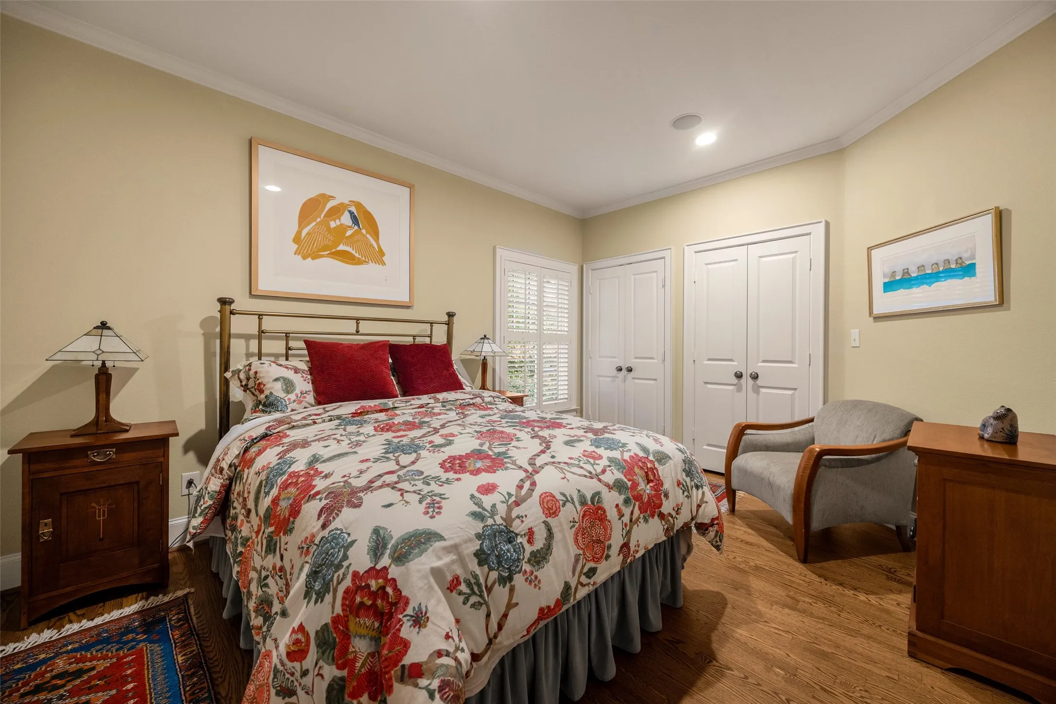 Bedroom featuring wood-finish flooring, crown molding, dual-panel closet doors, and interior shutters