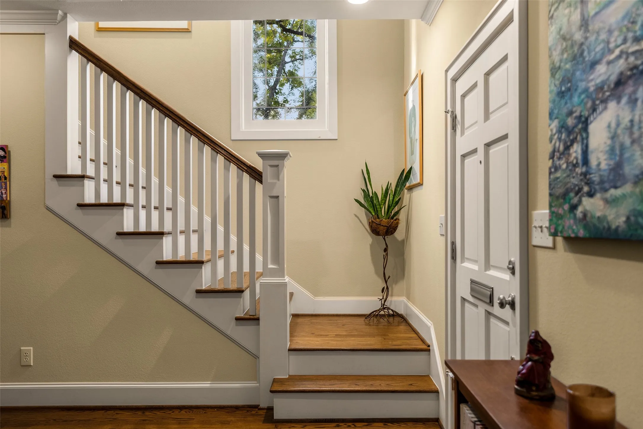 Foyer featuring a staircase with white balusters and wood-finish treads, a multi-pane fixed window, and a panelled exterior door with a built-in mail slot