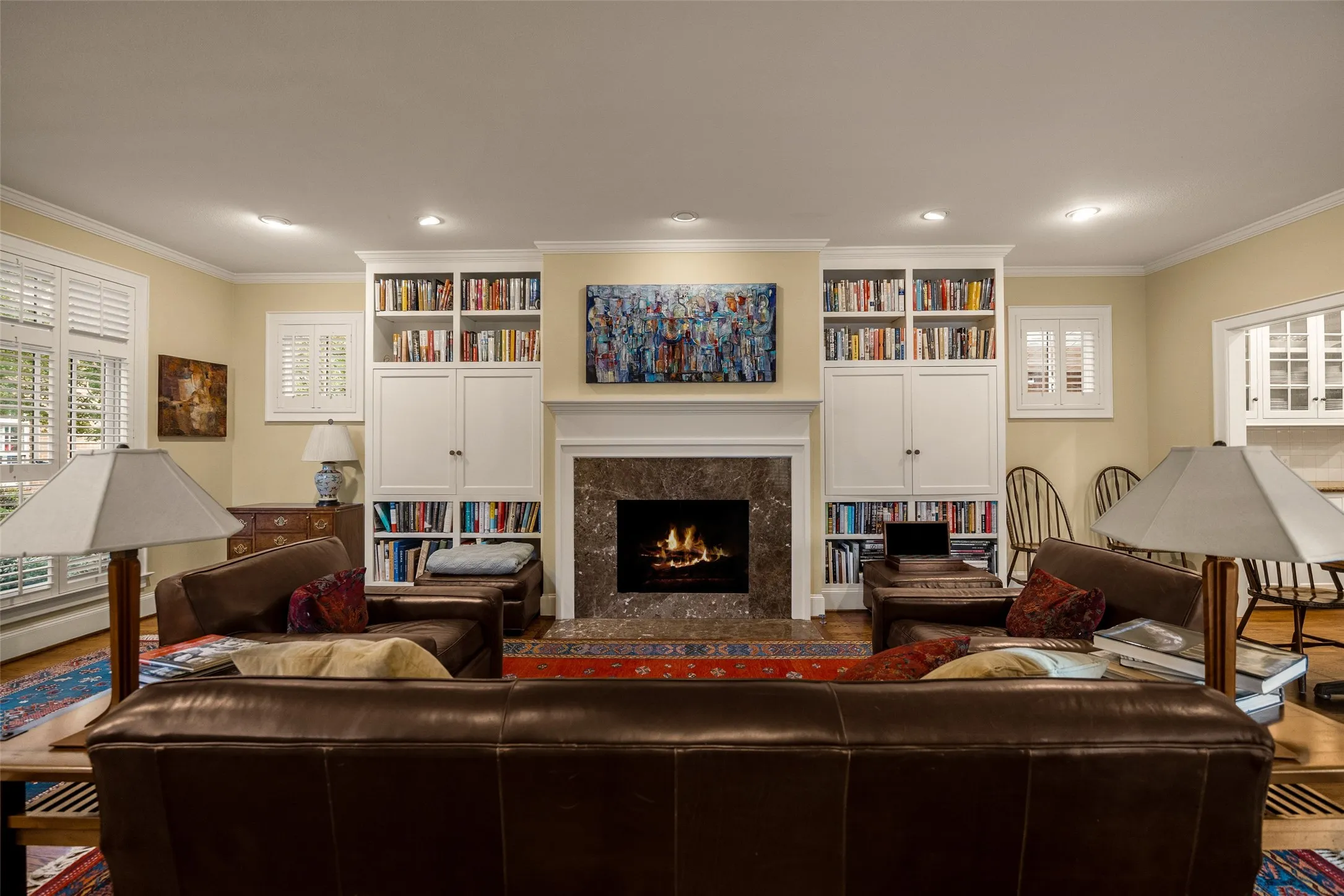 Floor-to-ceiling built-in cabinetry, stone-surround fireplace, and window shutters