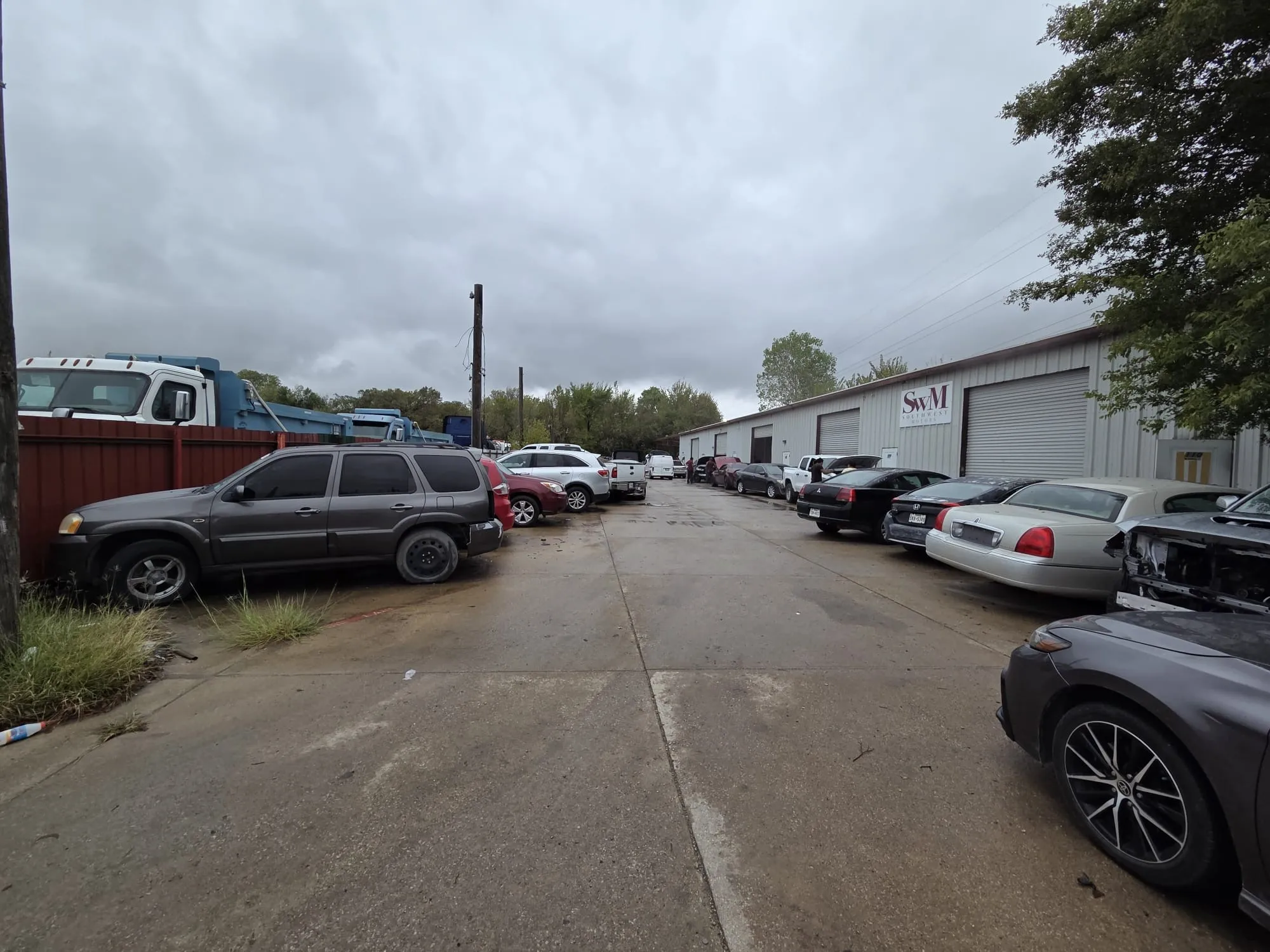 Industrial warehouse facility featuring metal exterior siding, multiple roll-up doors, and expansive concrete paved frontage