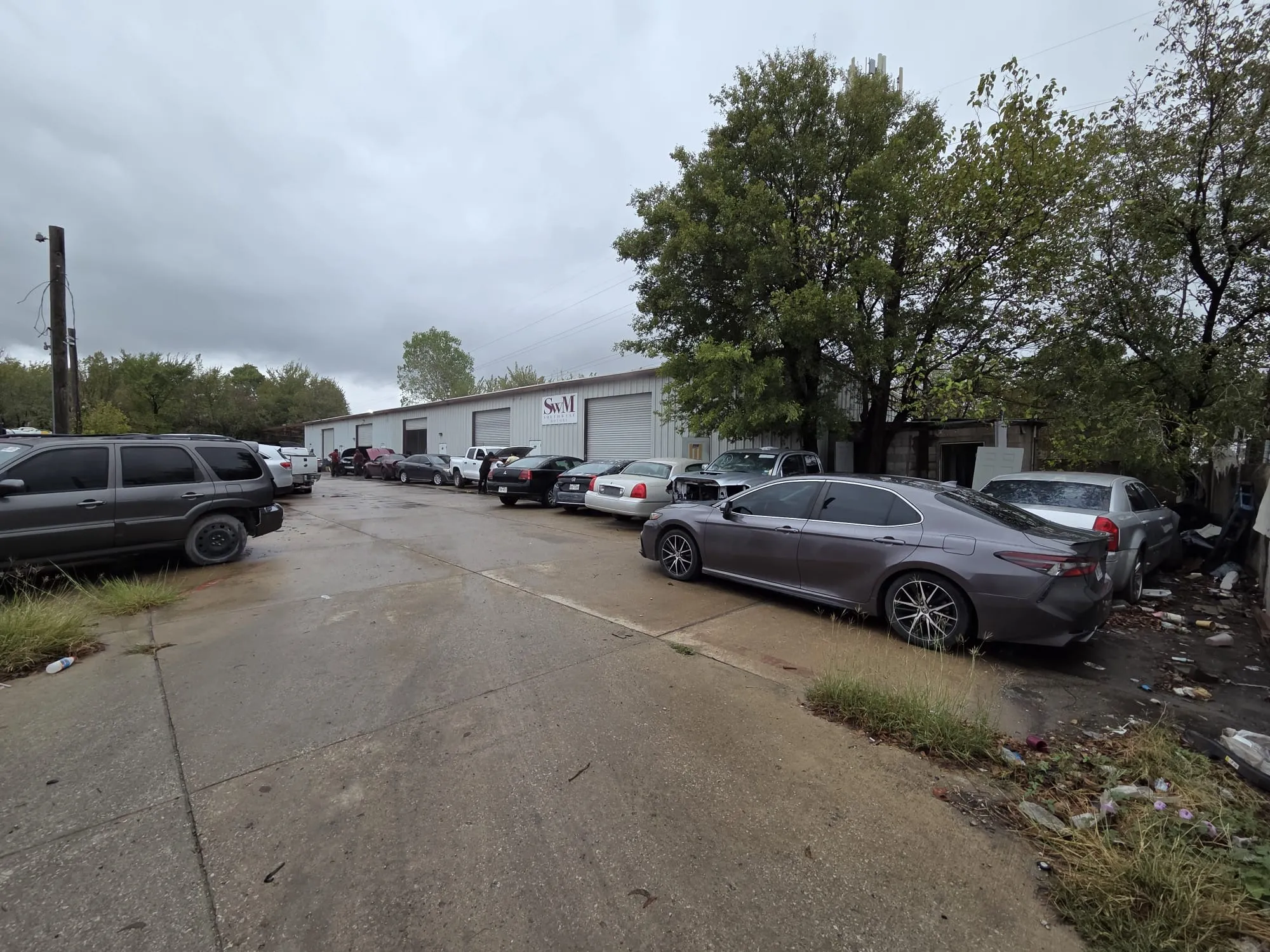 Industrial building featuring a metal exterior, multiple bay doors, and a paved concrete parking lot