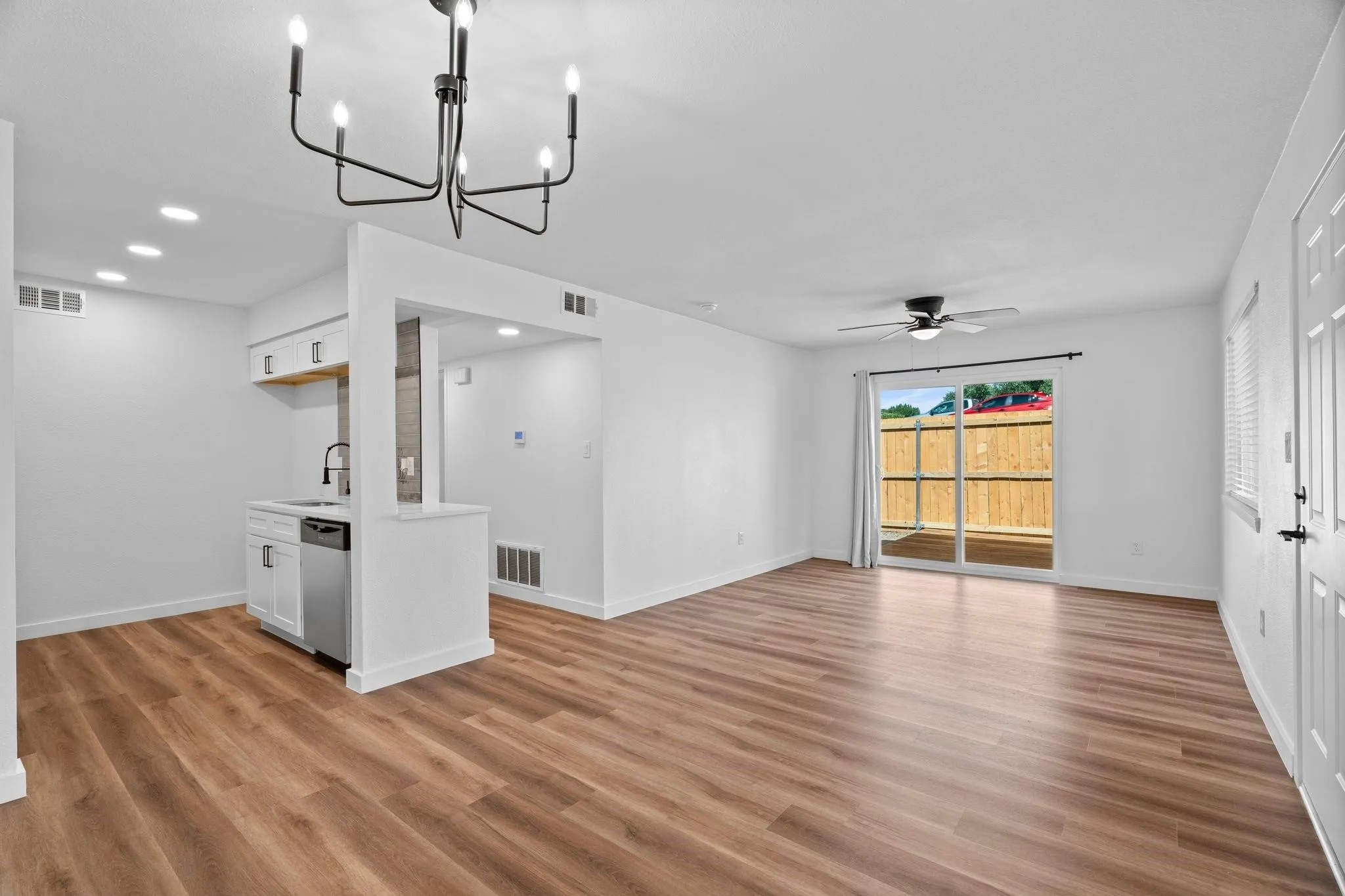 Open-concept area featuring wood-finish flooring, a contemporary six-arm chandelier, recessed lighting, a ceiling fan, and sliding glass doors