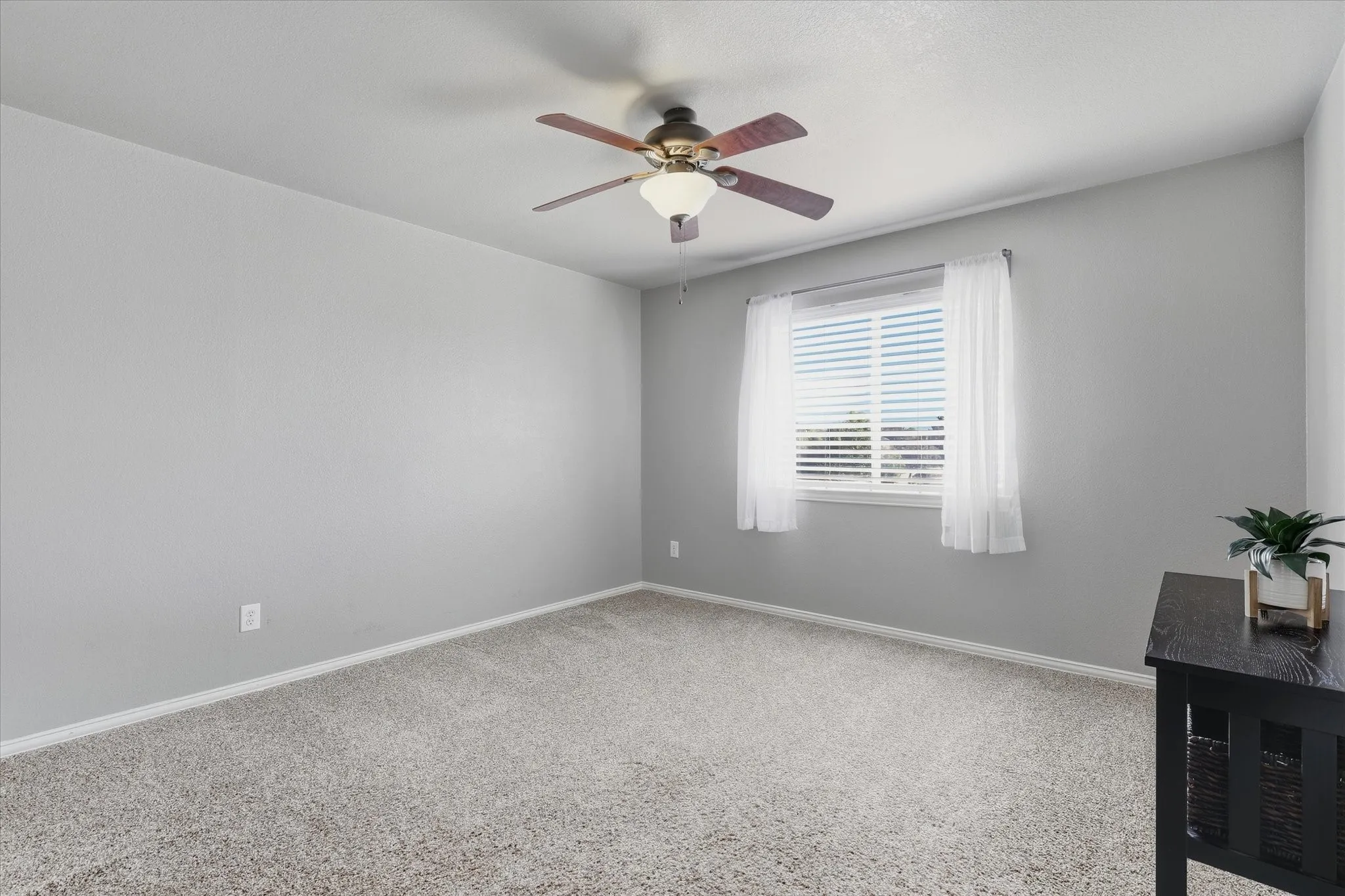 An upstairs secondary bedroom features a neutral palette, carpeting & natural light.