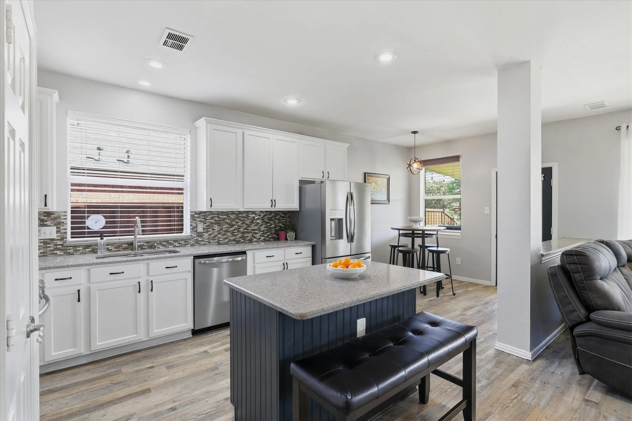 The expanded kitchen pairs classic white cabinetry with a contrasting navy island, adding storage, seating & generous space for meal preparation.