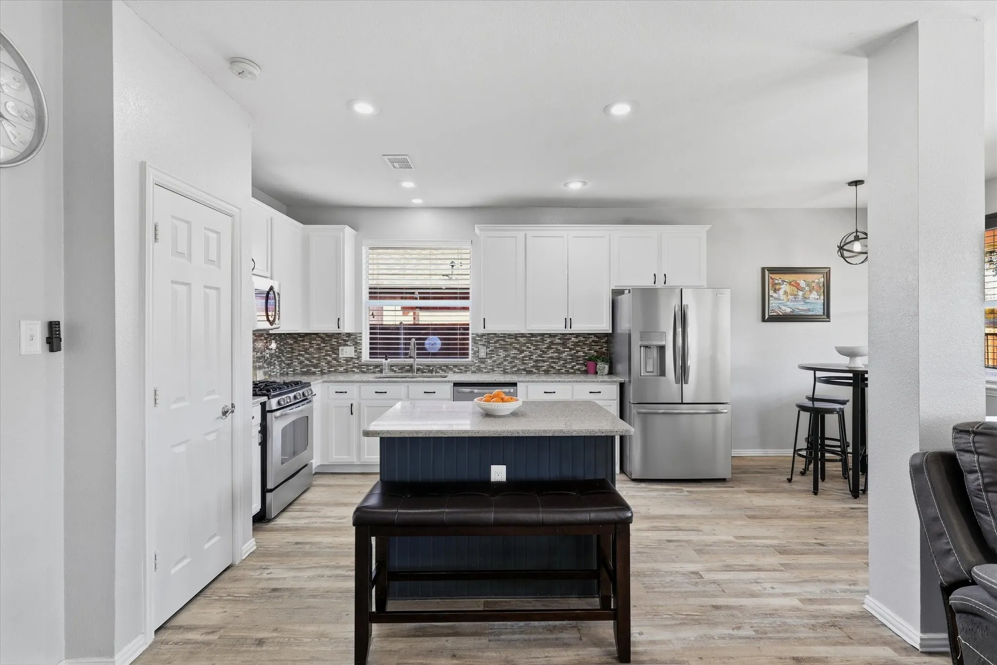 Updated countertops, a mosaic backsplash, decorative lighting & stainless-steel appliances, including a gas range, complete the space.