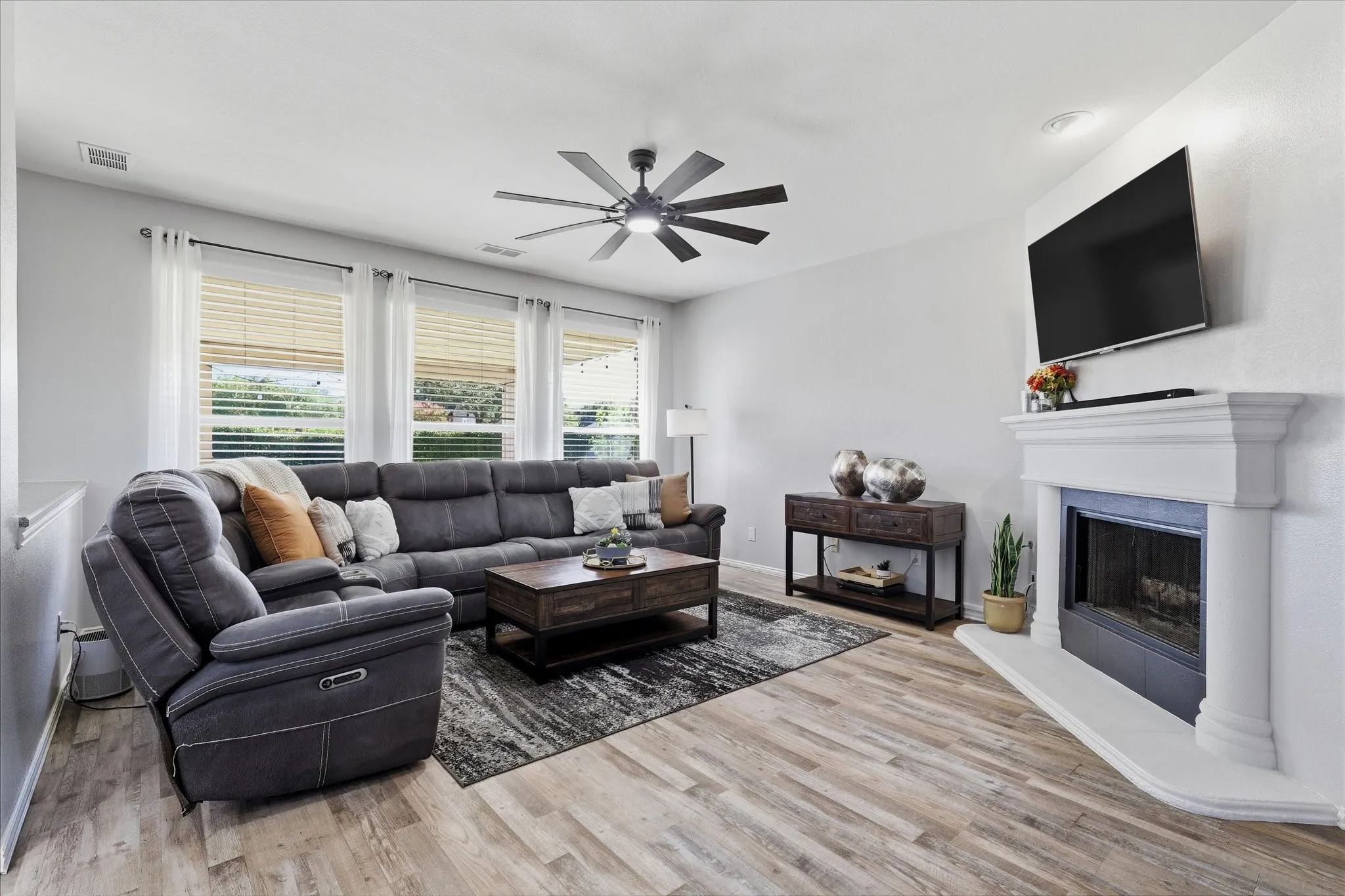 A fireplace with a crisp white mantel anchors the family room, where generous windows draw the outdoor setting inside.