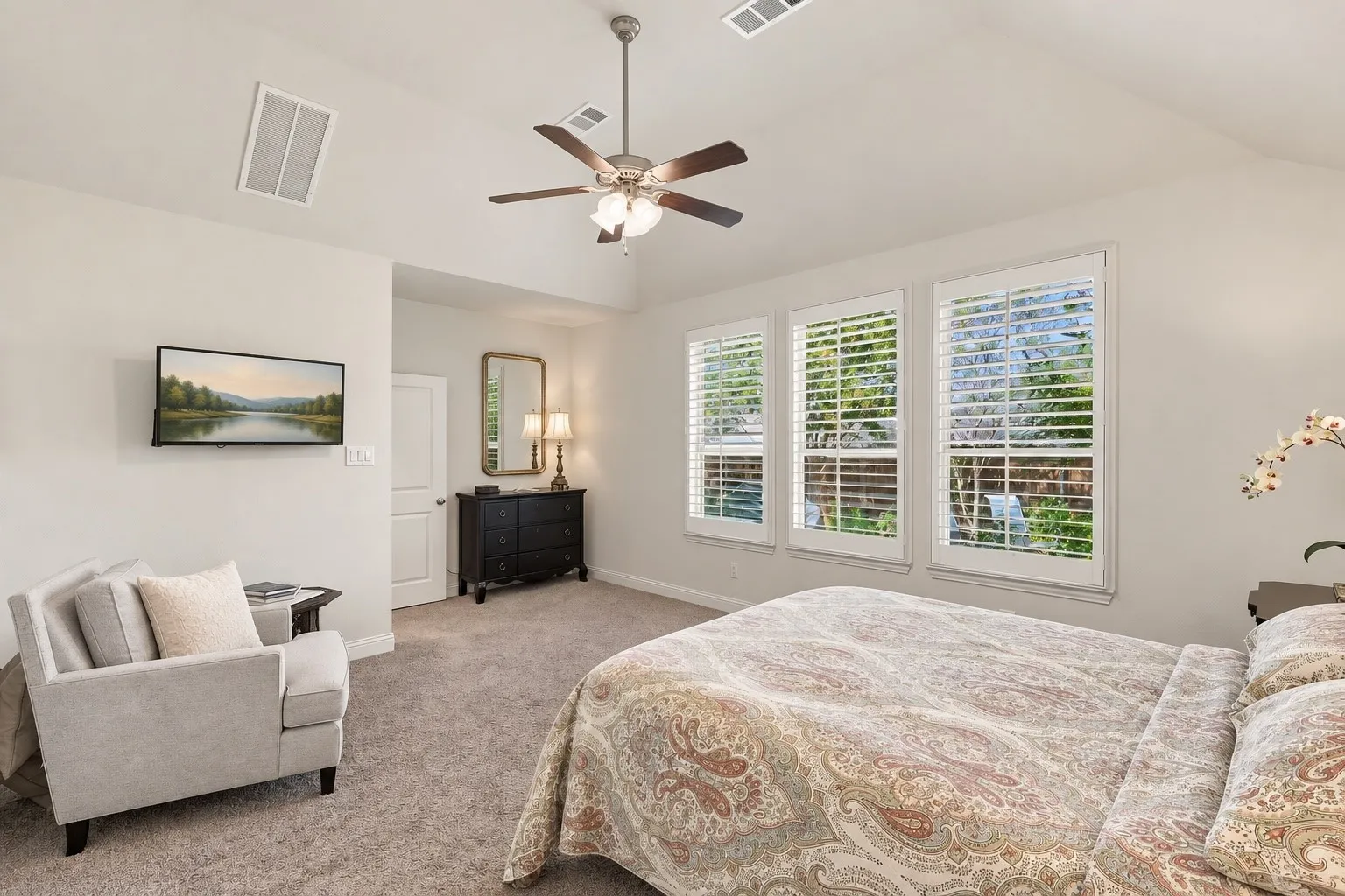 Vaulted ceilings, carpeting, central ceiling fan, and windows featuring integrated plantation shutters