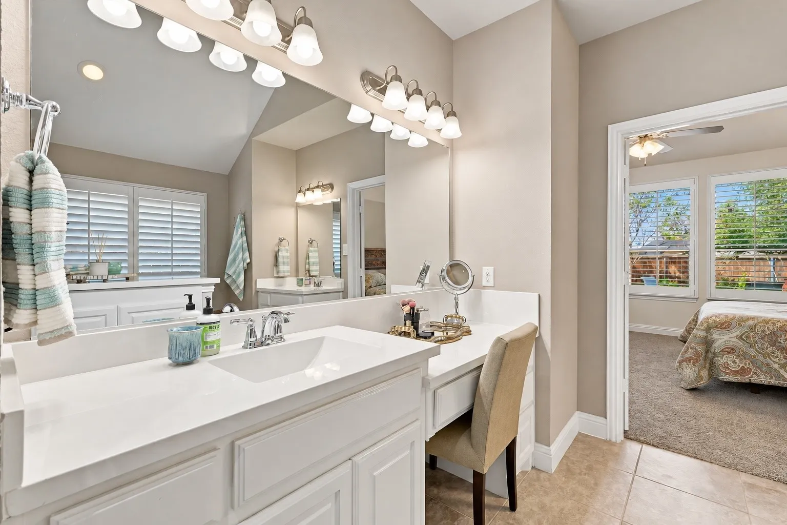 Dual-sink vanity featuring white cabinetry, solid-surface countertop, integrated rectangular basins, and multi-bulb polished chrome vanity lighting