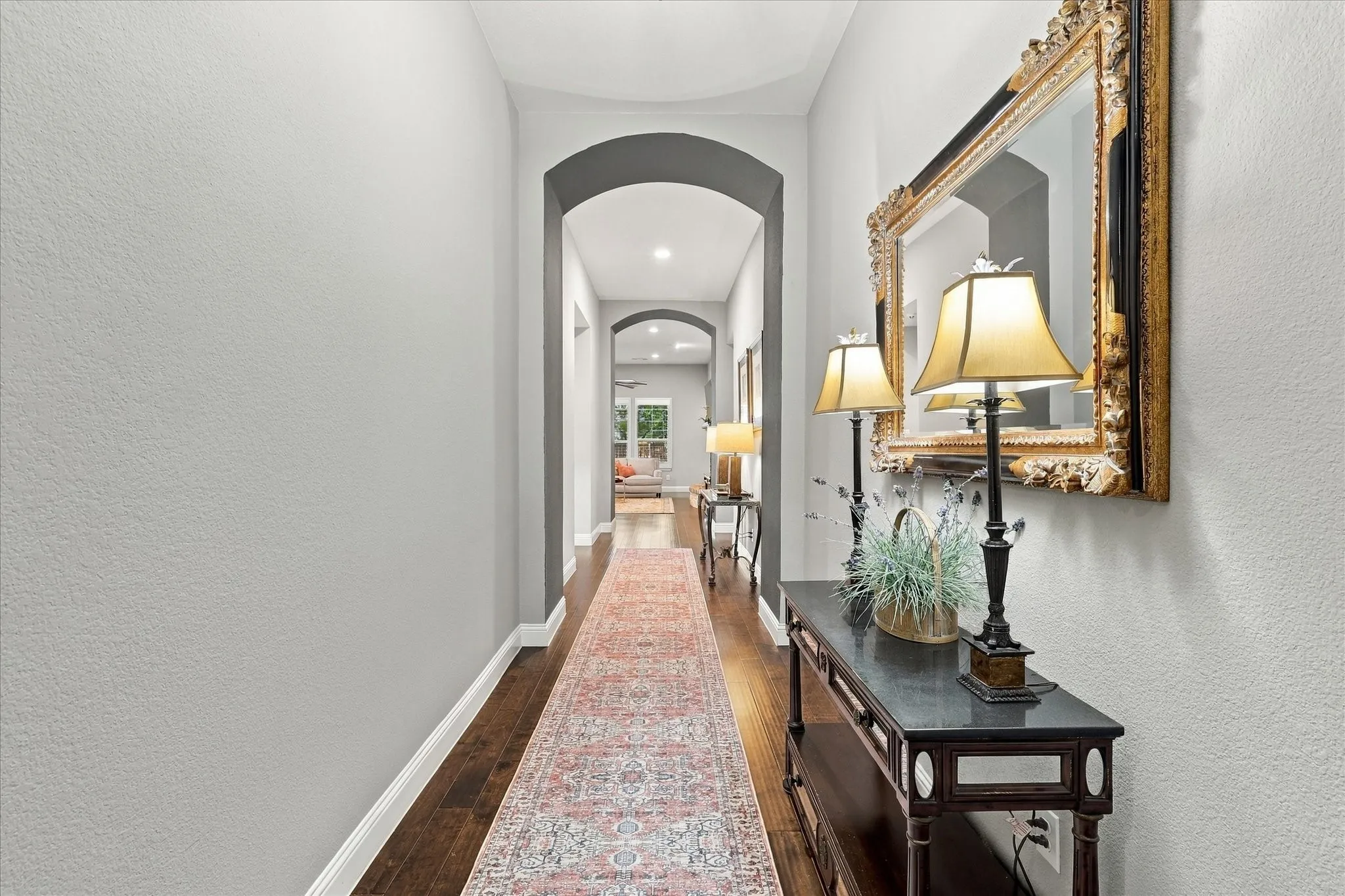 Hallway featuring wood-finish flooring, recessed lighting, and dual arched entryways