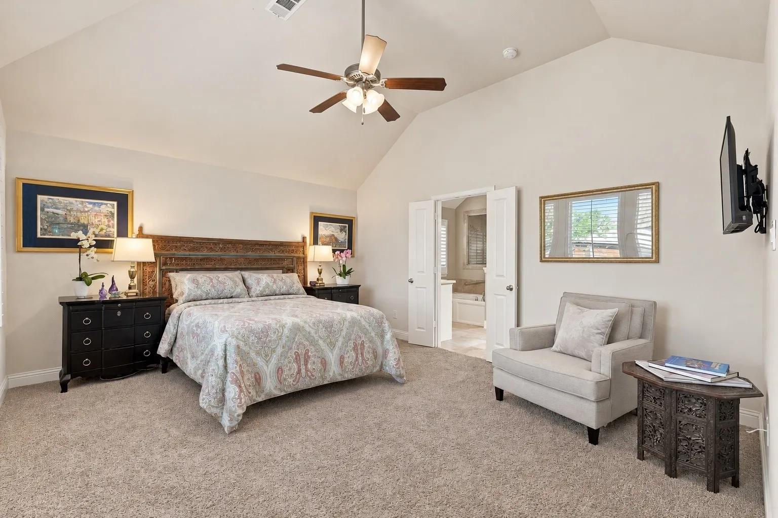 Vaulted ceilings, neutral carpeting, and a ceiling-mounted light fixture with fan