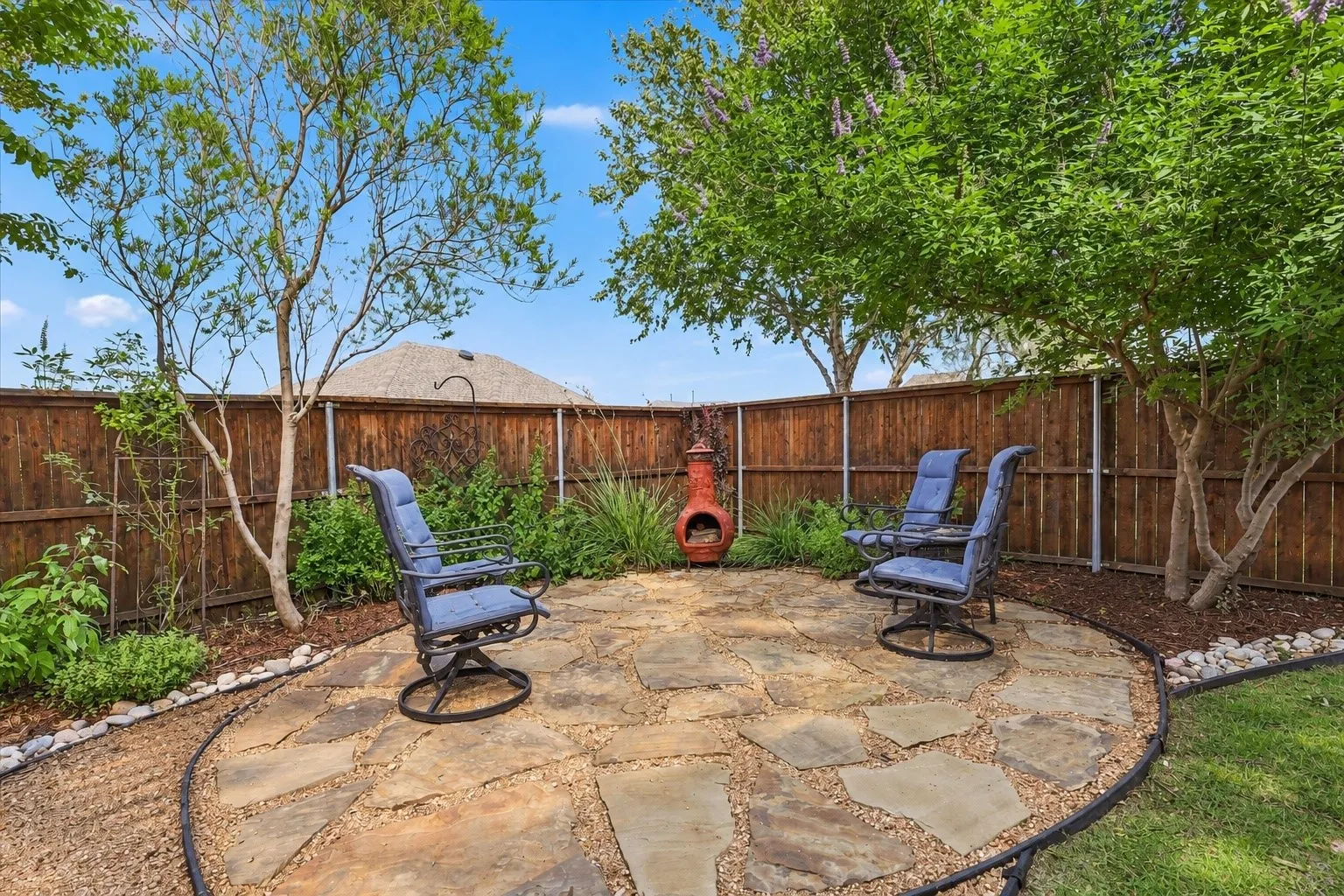 Flagstone patio featuring gravel infill, enclosed by wood privacy fencing and mature trees