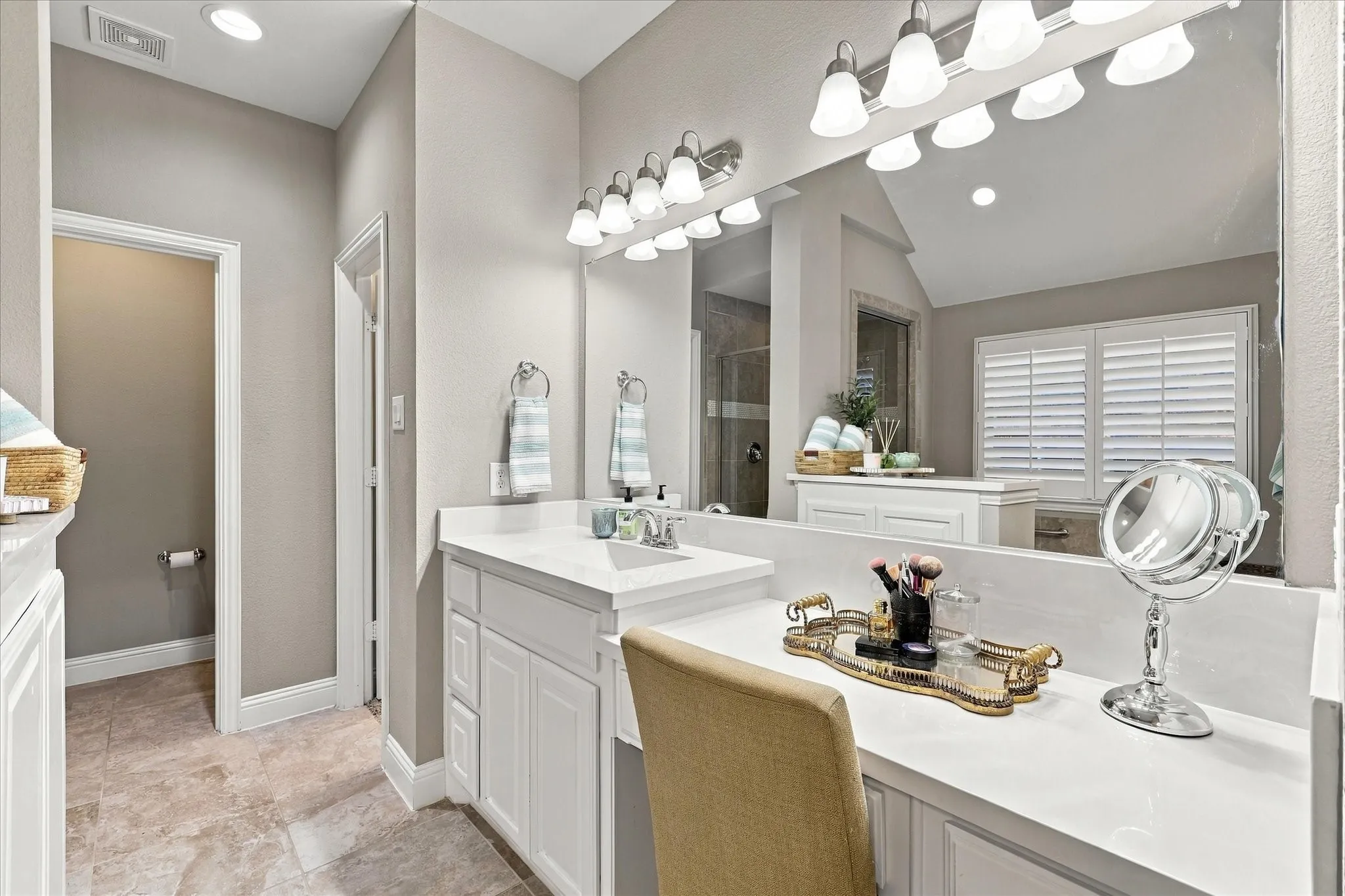 Bathroom featuring a double vanity with white cabinetry, integrated sink, stone-surface countertop, dual vanity mirrors, and multi-light fixtures