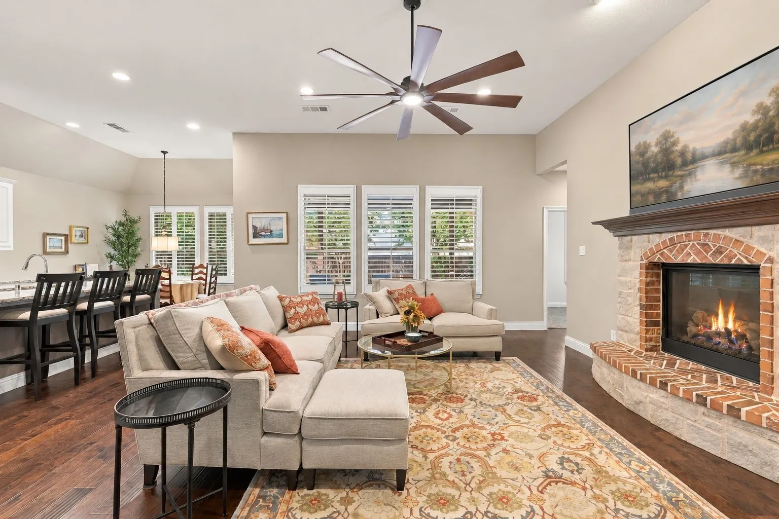 Open-concept living space featuring wood-finish flooring, recessed lighting, and gas fireplace to tie in the center of the room