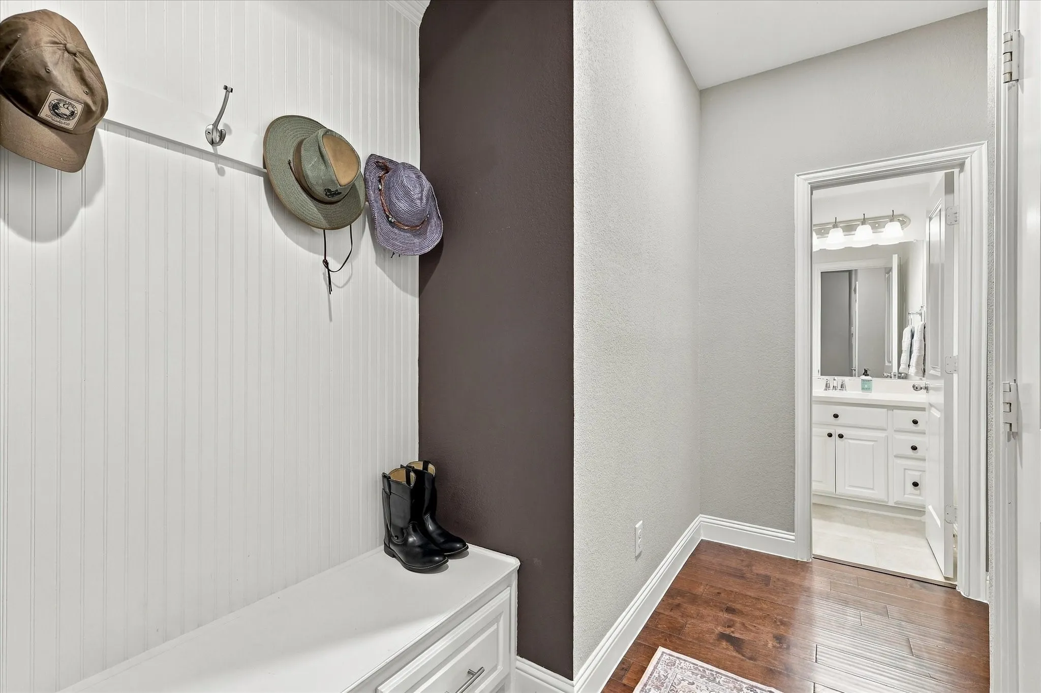 Built-in cabinetry featuring beadboard detailing, integrated wall-mounted hooks, and a solid-surface bench seat