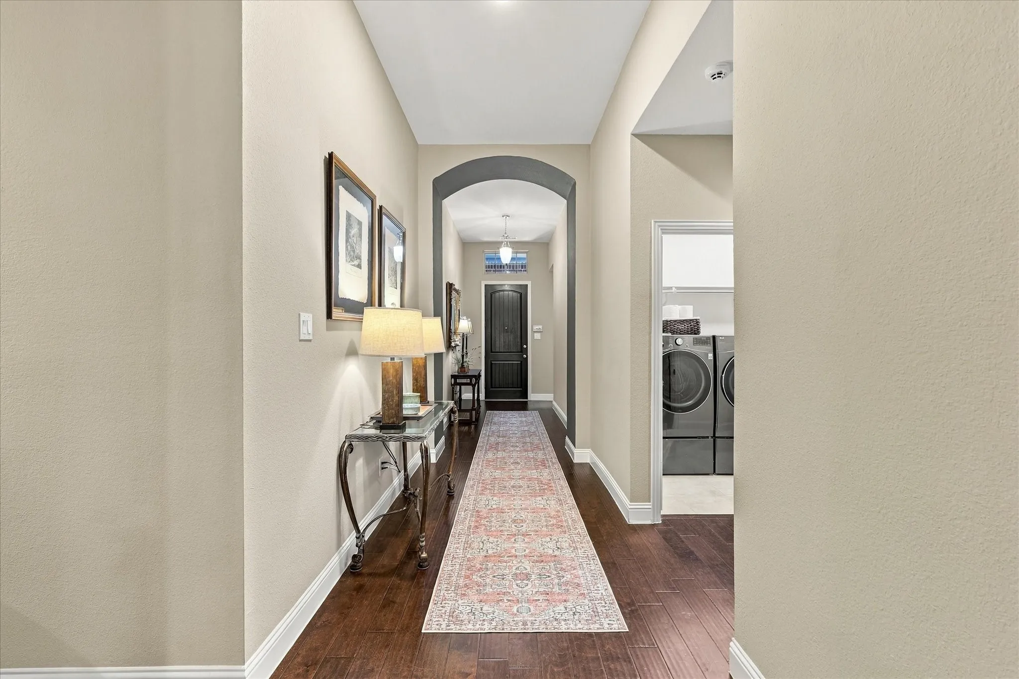 Entry hallway featuring dark wood-finish flooring, a decorative arched entryway, and an exterior door with a transom window