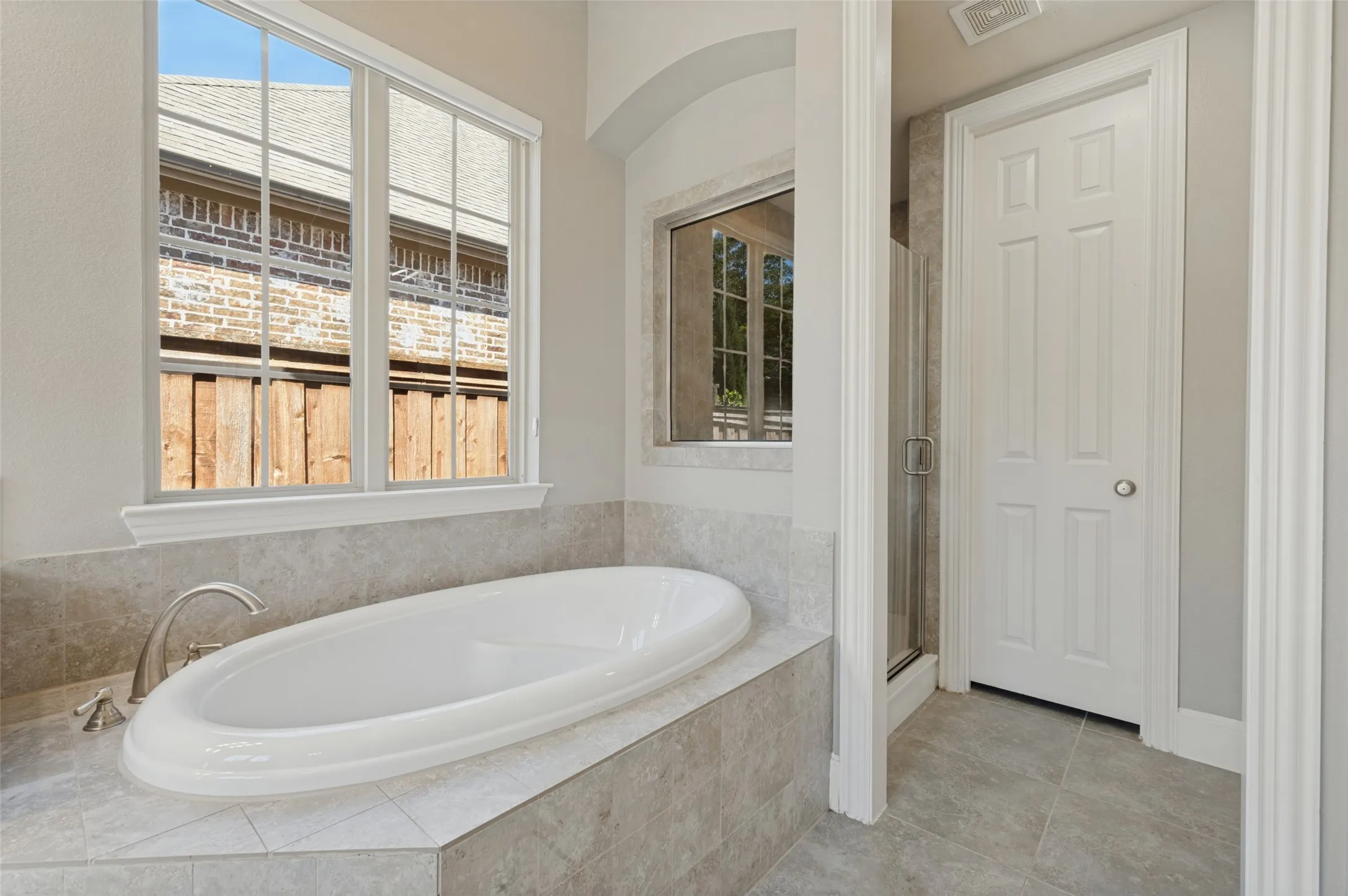 First floor primary suite with generous space and an ensuite bath featuring separate vanities, a soaking tub and separate shower.