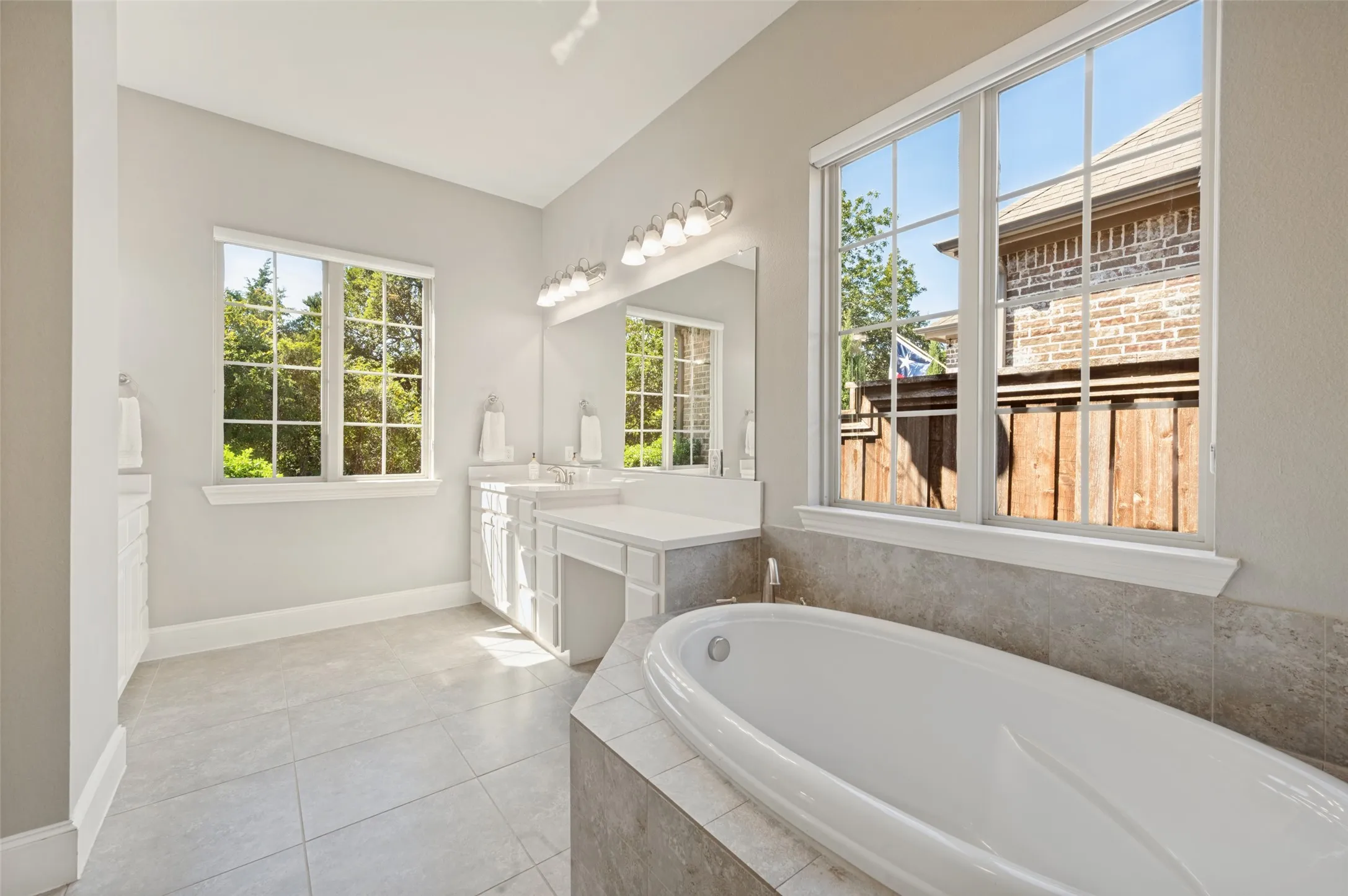 First floor primary suite with generous space and an ensuite bath featuring separate vanities, a soaking tub and separate shower.