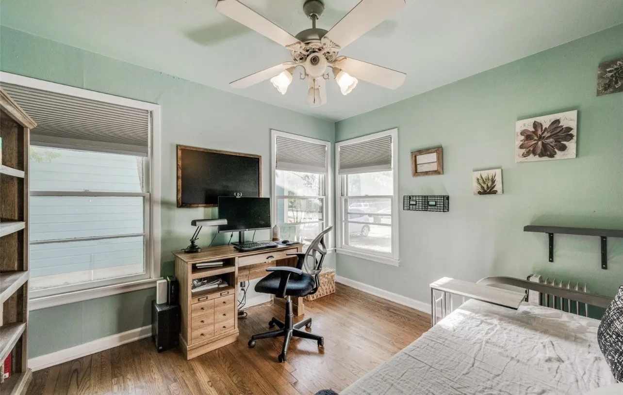 Wood-finish flooring, multi-pane windows with integrated blinds, and a ceiling-mounted fan with light fixture