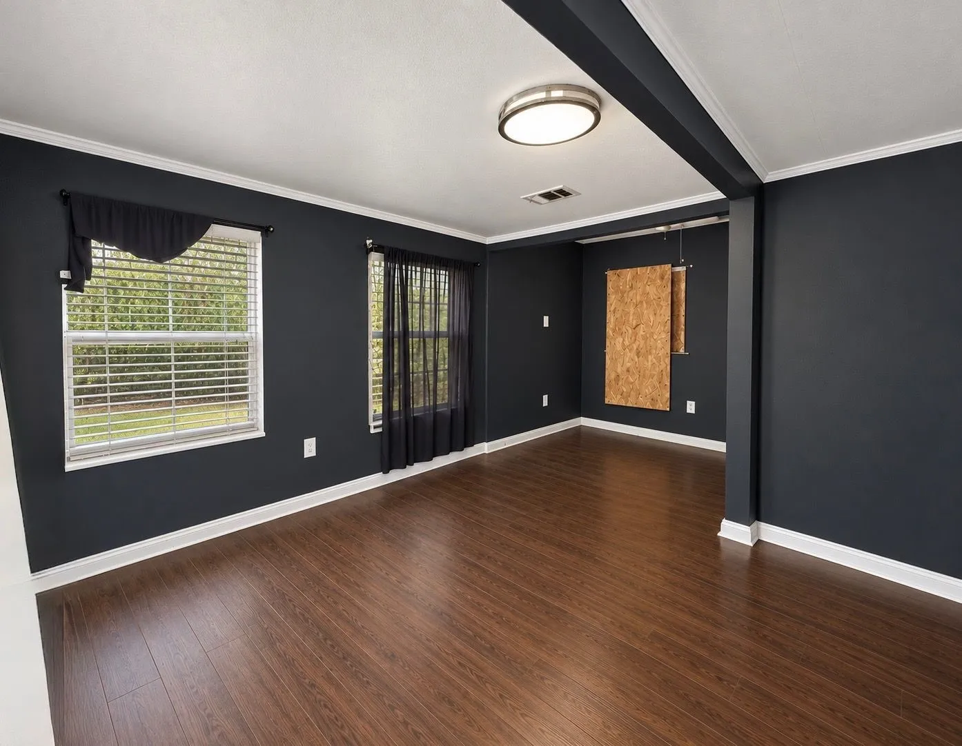 Interior featuring dark-toned walls, wood-finish flooring, crown molding, double-pane windows, and a flush-mount ceiling light fixture