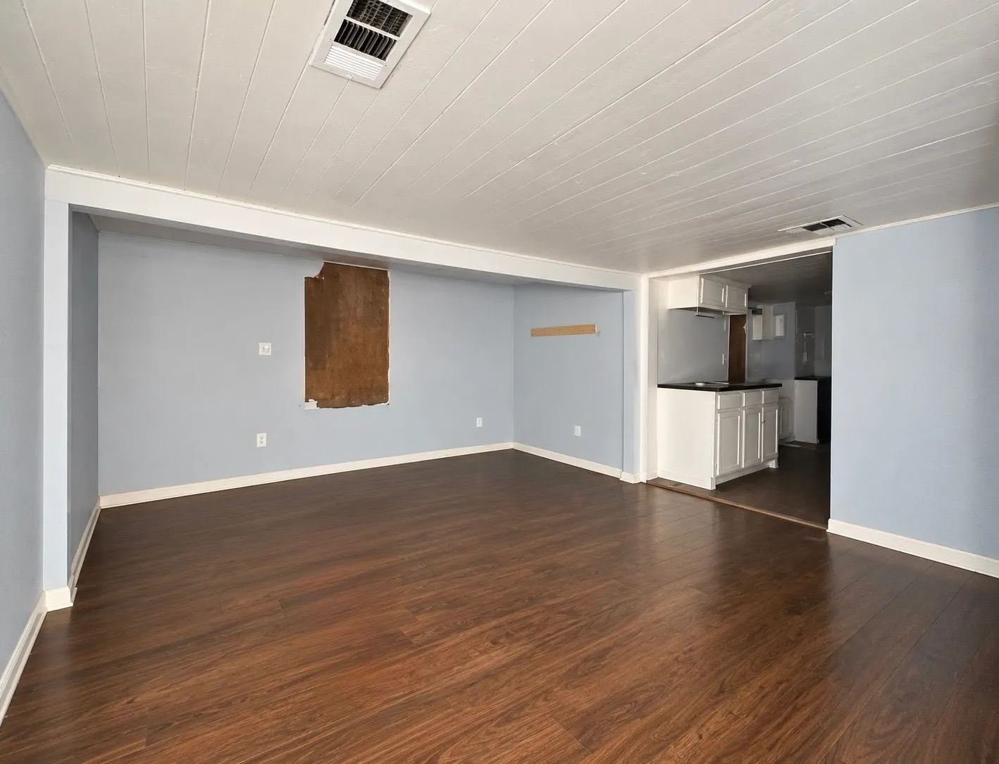 Interior space featuring wood-finish flooring, a white paneled ceiling, and built-in white cabinetry with a dark countertop