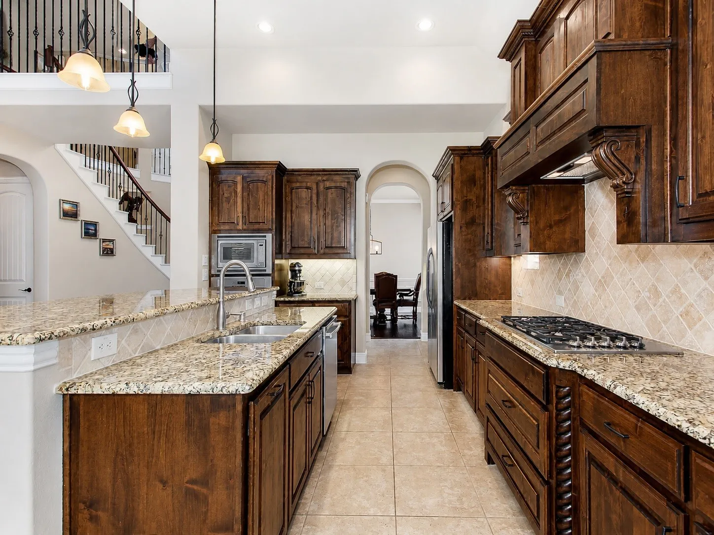 Gourmet kitchen featuring custom wood cabinetry, granite countertops, a gas cooktop, built-in appliances, and tile flooring