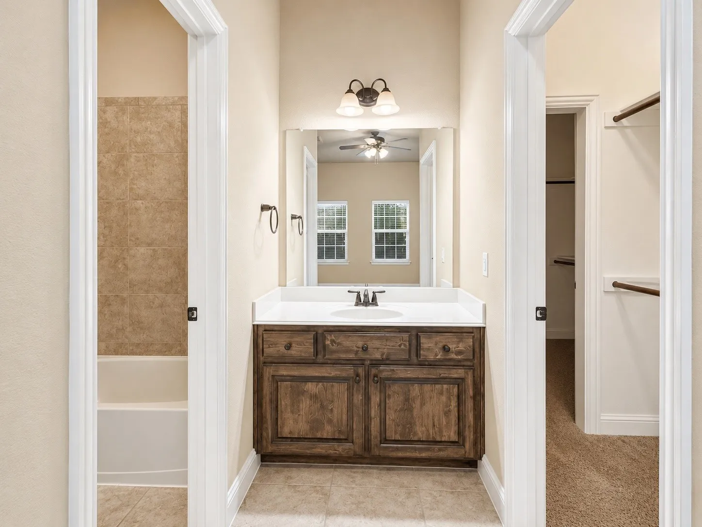 Bathroom vanity with a white countertop and integrated sink, complemented by a wood-finish cabinet with dark hardware