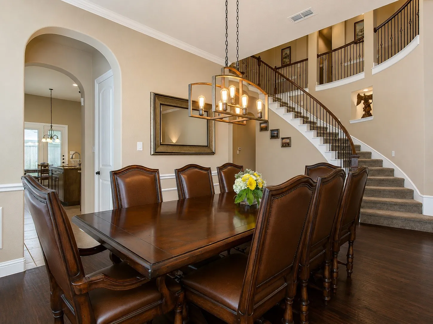 Formal dining area featuring rich wood-finish flooring, an arched doorway, and a contemporary chandelier