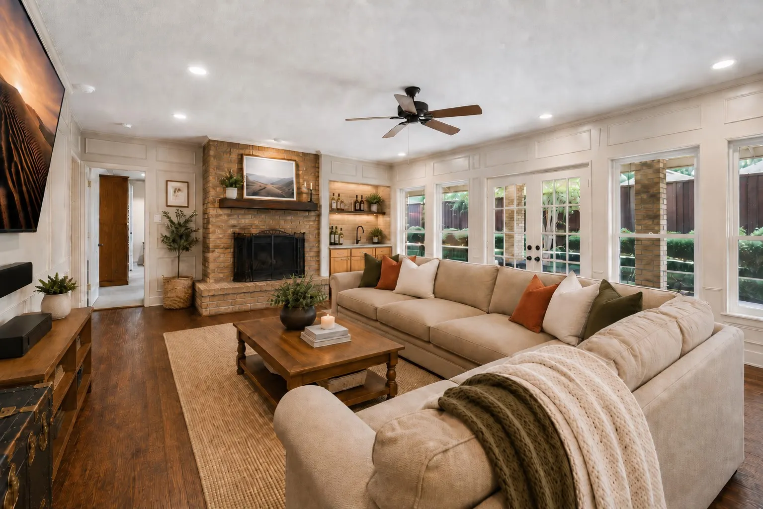 Stone-clad fireplace with a wood-finish mantel, wood-finish flooring, recessed lighting, ceiling fan, and French doors