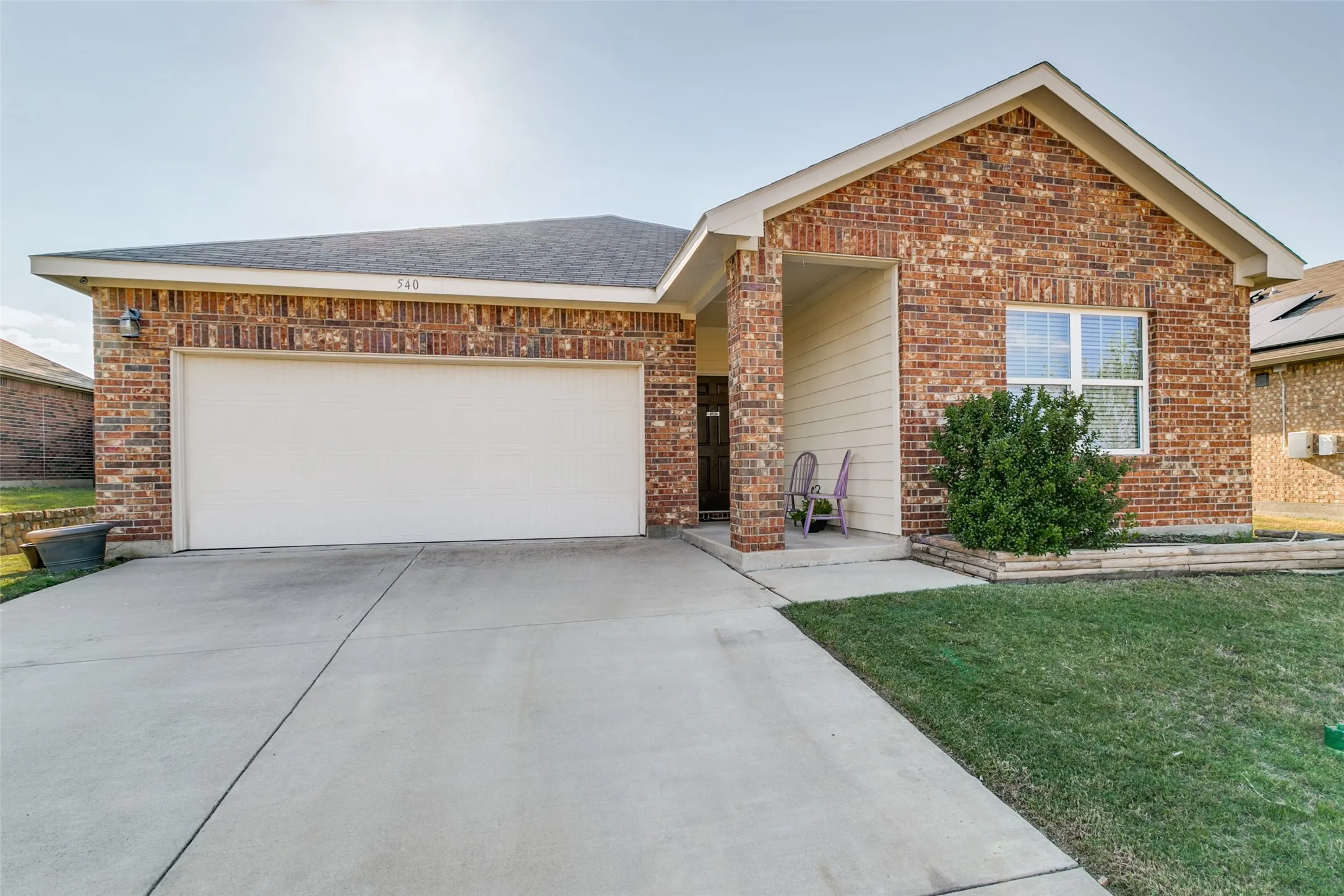 Single-story brick exterior featuring a covered entryway, concrete driveway, and attached two-car garage