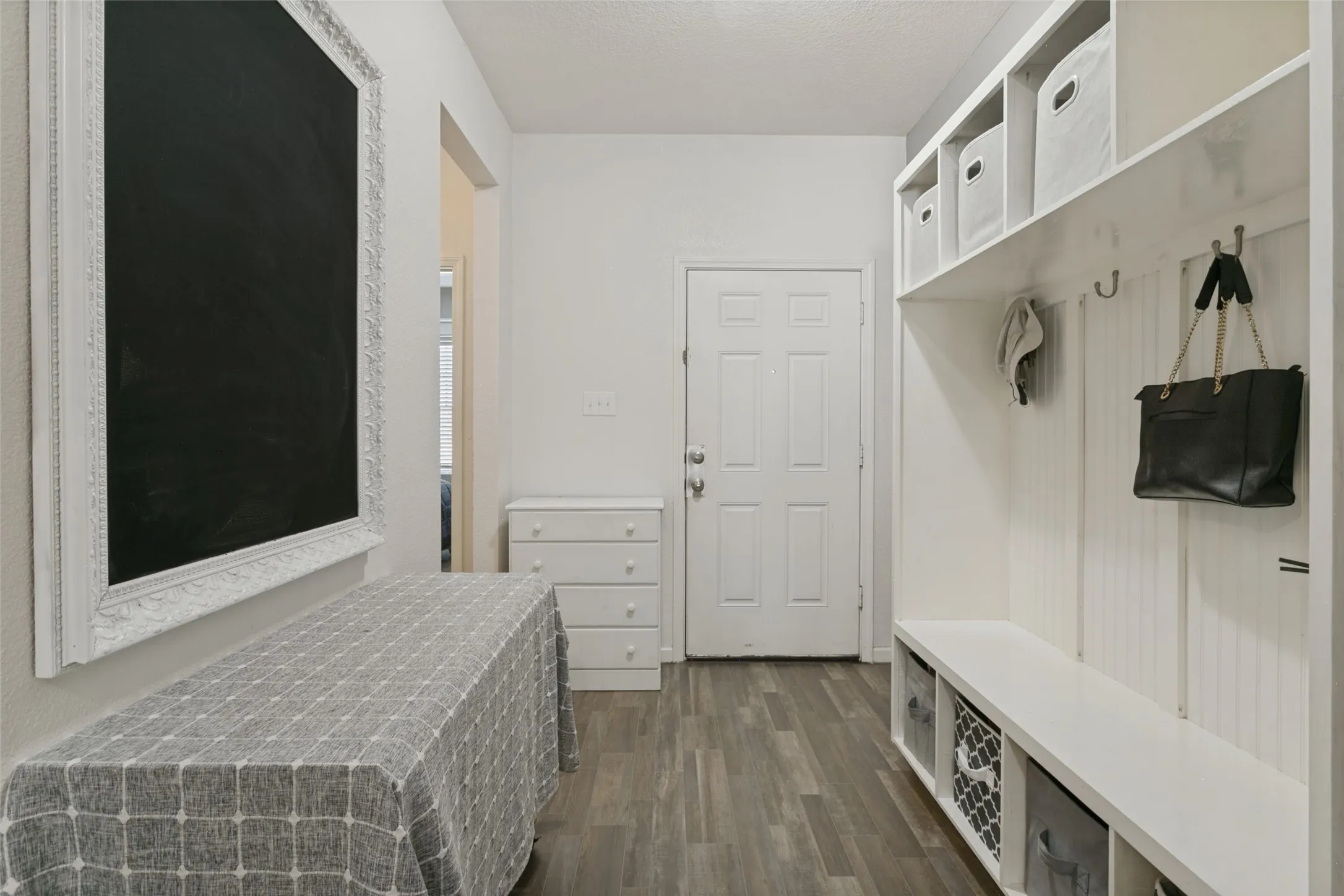 Built-in white storage cabinetry with open cubbies and beadboard detailing, paired with wood-finish flooring