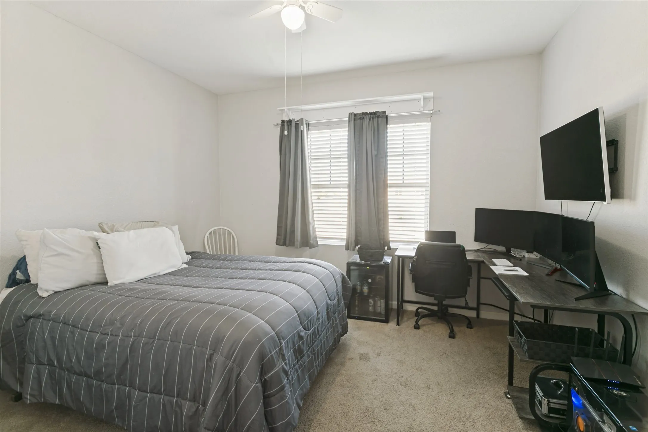 Neutral-toned room featuring wall-to-wall carpeting, a central ceiling fan with integrated lighting, and a multi-pane window