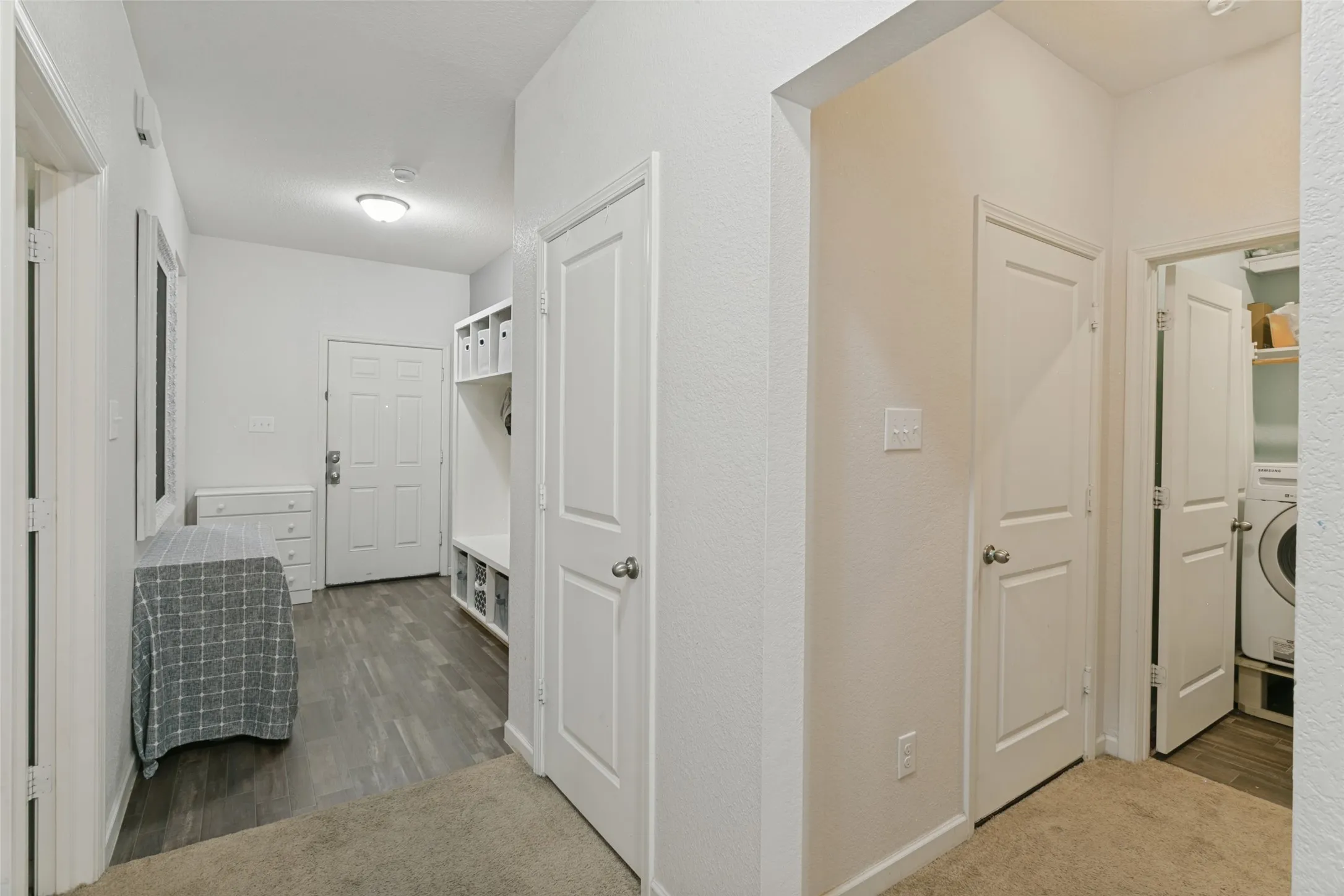 Interior entry area featuring wood-finish flooring, built-in shelving, white paneled doors, and recessed lighting