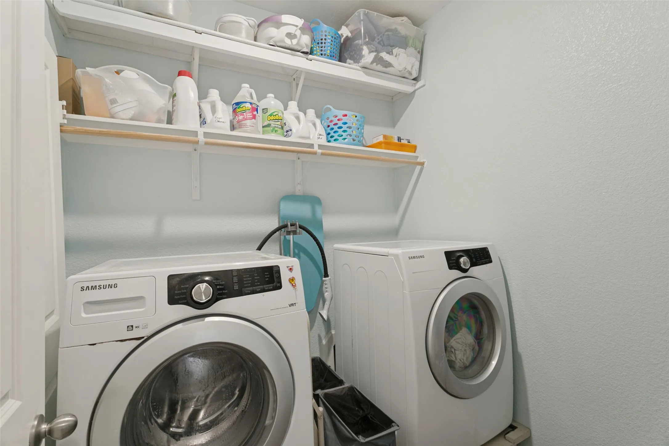 Utility area featuring two levels of wall-mounted open shelving and a dedicated space for laundry appliances