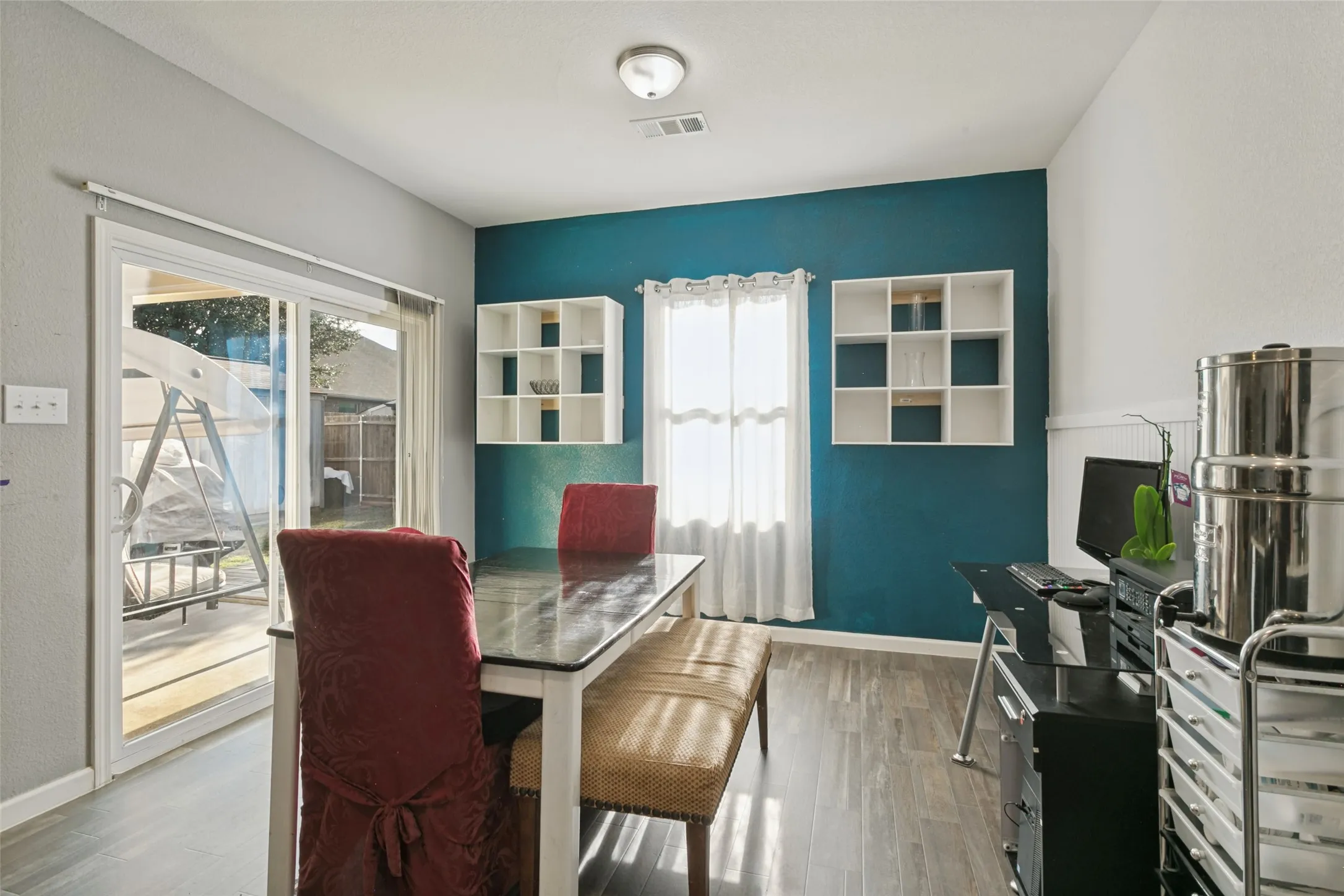 Room featuring wood-finish flooring, built-in white shelving, and a sliding glass door