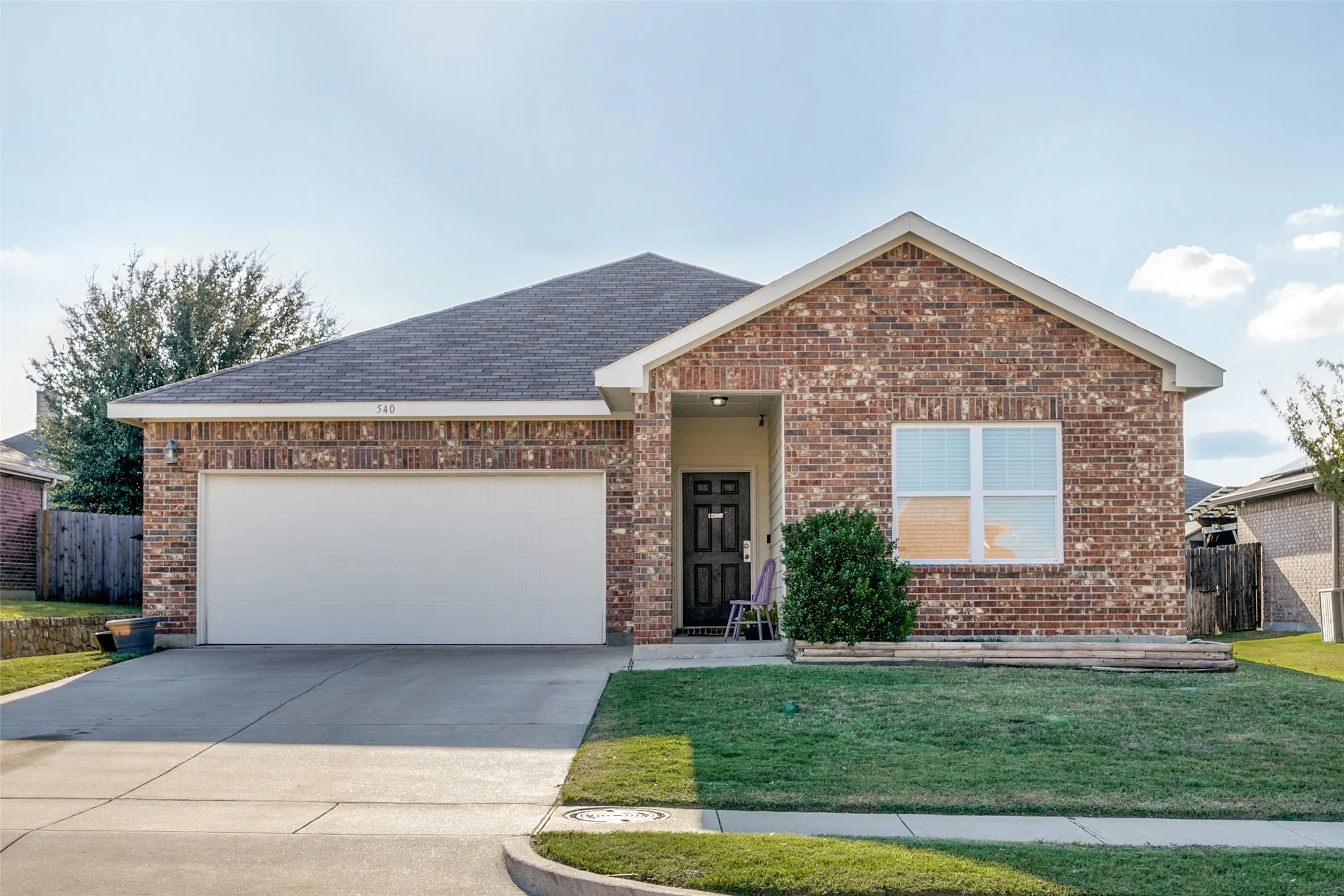 Brick exterior facade featuring a recessed covered entryway, dual-pane windows, and a concrete driveway leading to an attached two-car garage