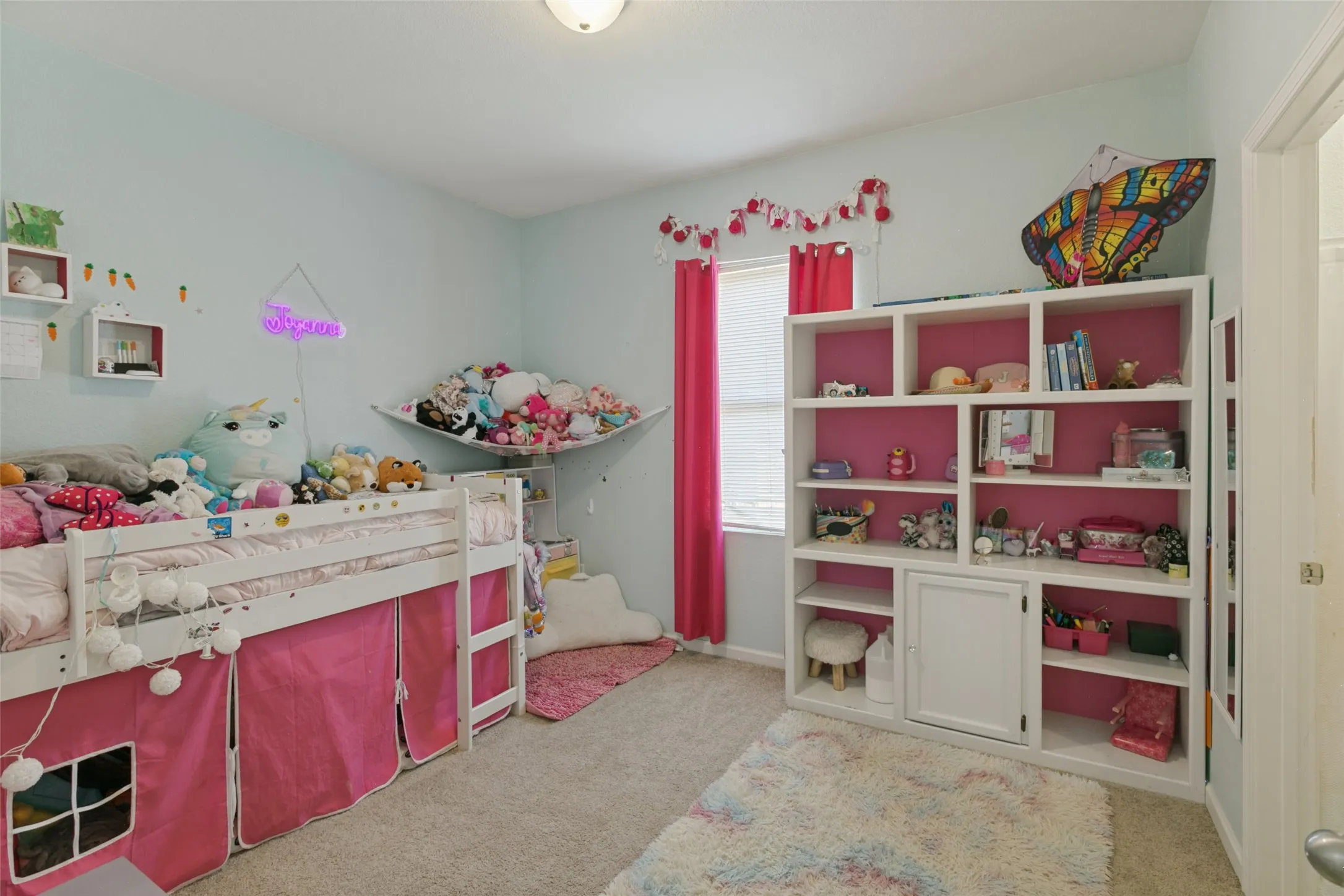 Built-in white shelving unit with integrated lower cabinetry and neutral wall-to-wall carpeting
