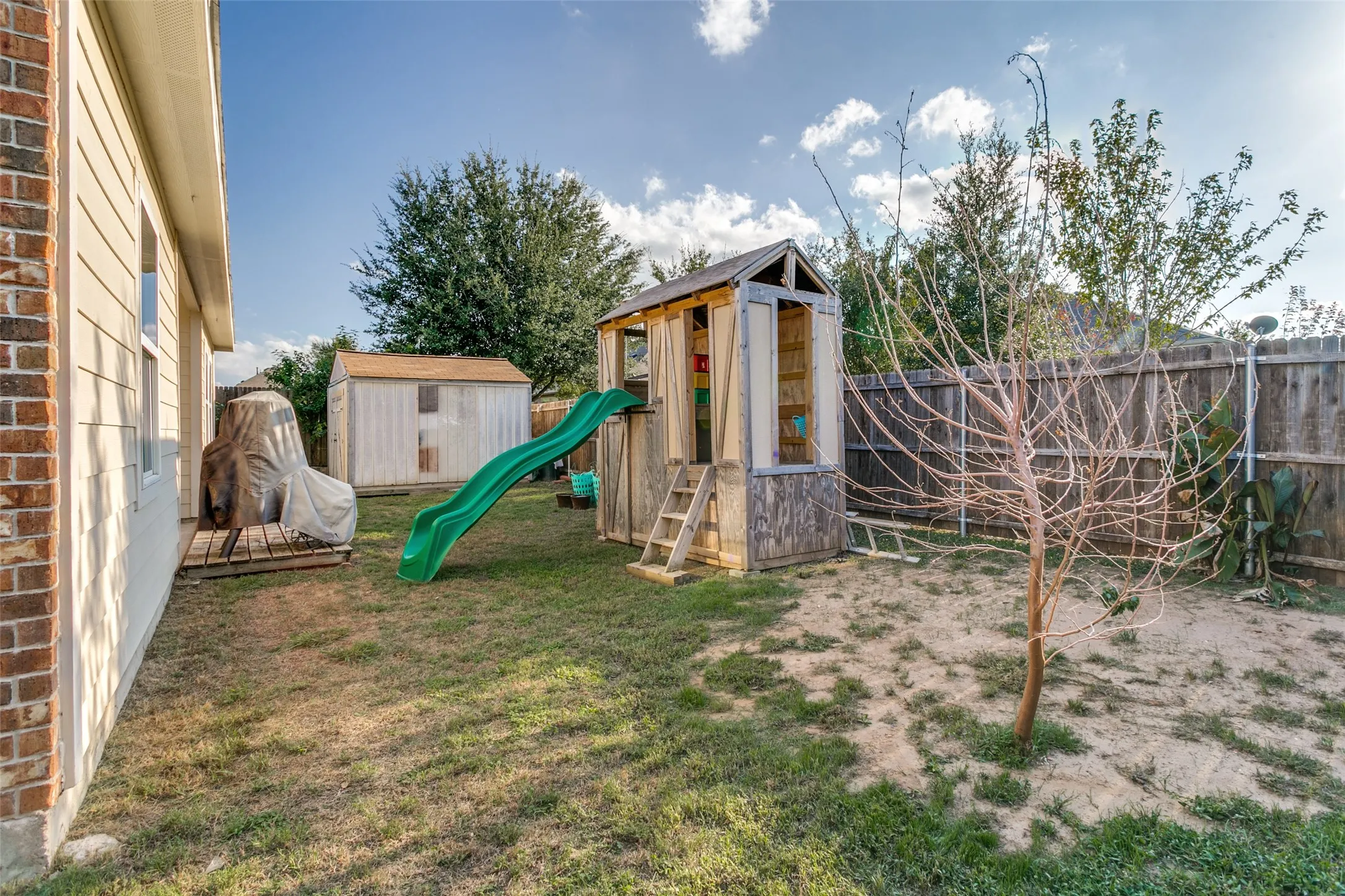 Rear yard featuring a wood fence enclosure, detached storage structure, and brick exterior wall