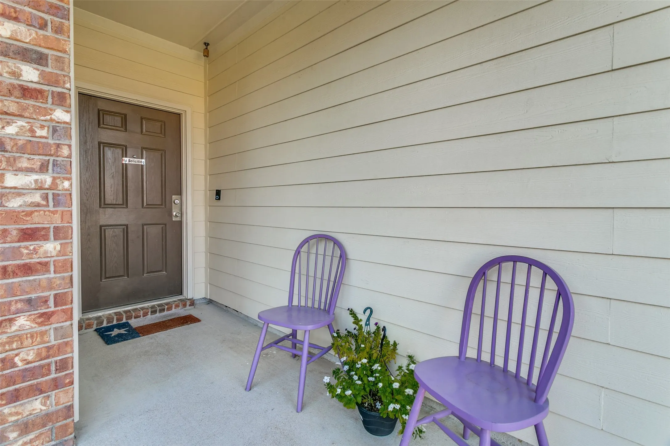 Covered entryway featuring light-toned horizontal siding, a multi-panel door, and masonry exterior accent