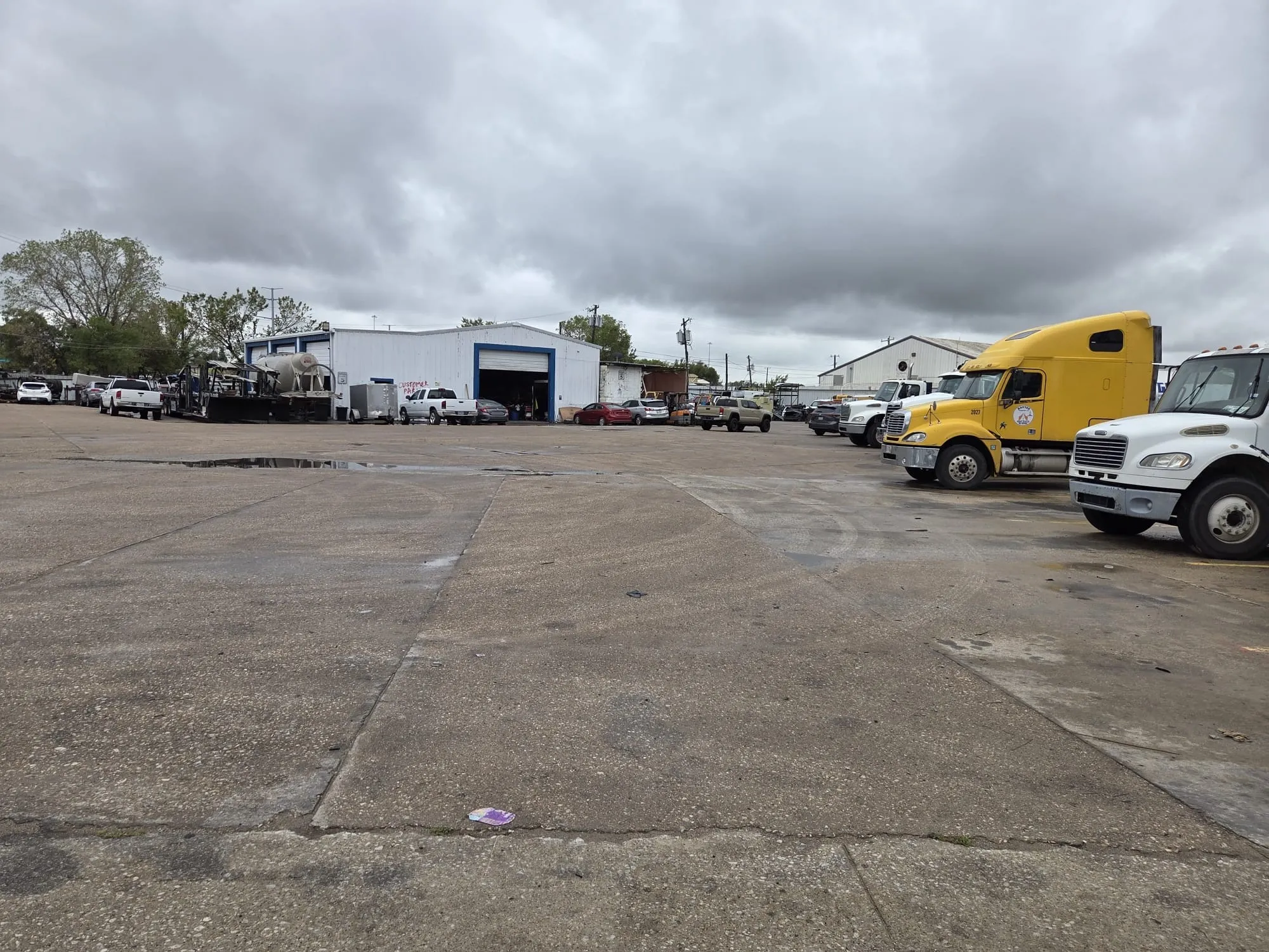 Industrial facility featuring a large concrete lot and high-clearance metal workshop building