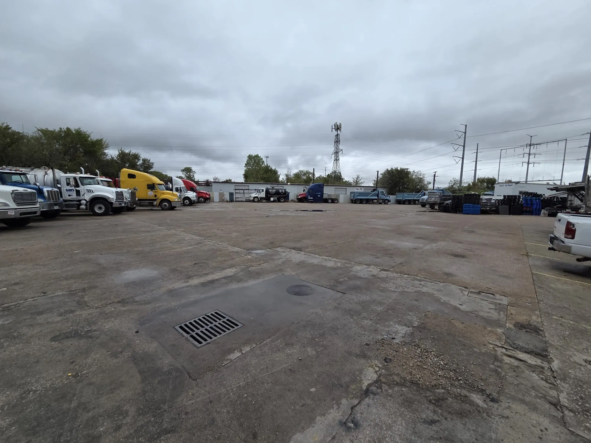 Expansive concrete industrial lot featuring integrated drainage systems and perimeter fencing