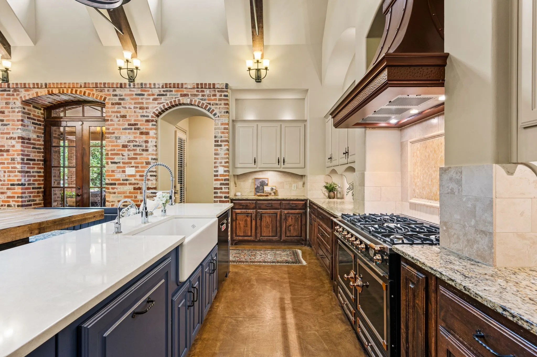 A stunning copper vent hood takes center stage above the exquisite La Cornue range, while abundant cabinetry provides exceptional storage, blending timeless elegance with everyday functionality.
