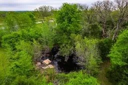 Wooded lot featuring mature deciduous trees and a natural rock formation