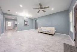 Open living area featuring stone-finish tile flooring, recessed lighting, ceiling fan, and pass-through window