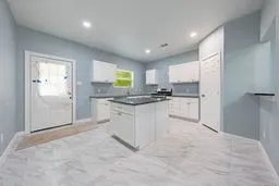 Kitchen featuring white cabinetry, a center island with a dark countertop, recessed lighting, and tile flooring