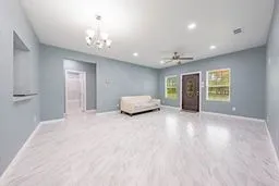 Open-concept interior featuring wood-finish flooring, recessed lighting, a multi-light chandelier, and a decorative front door with inset glass