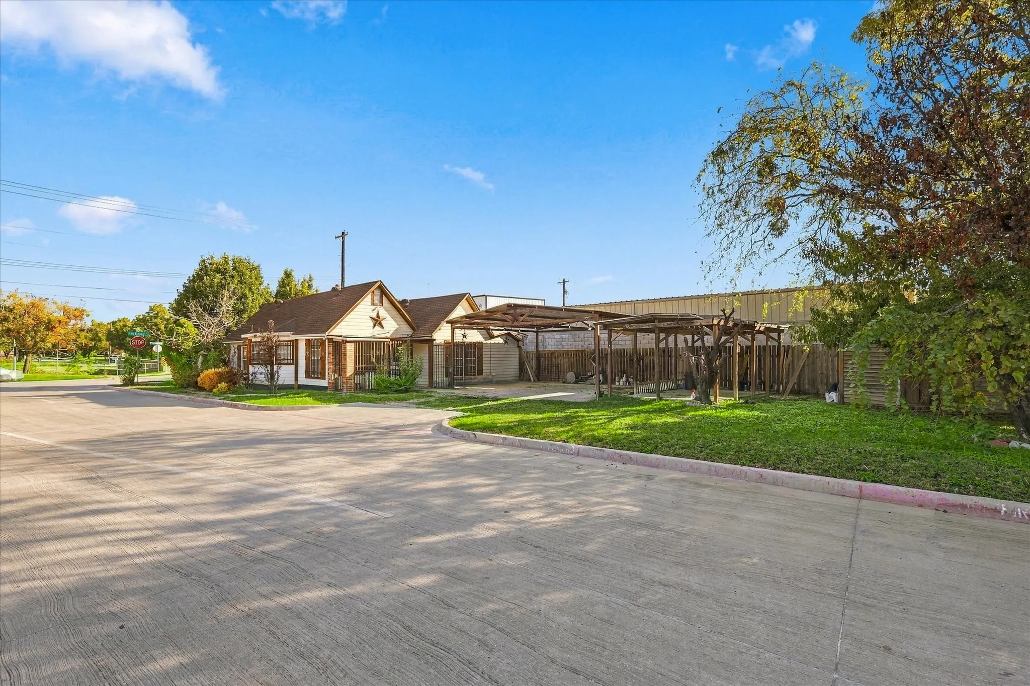 Single-story exterior featuring a brick facade, decorative star accent, asphalt shingle roofing, and an attached multi-bay open-air carport