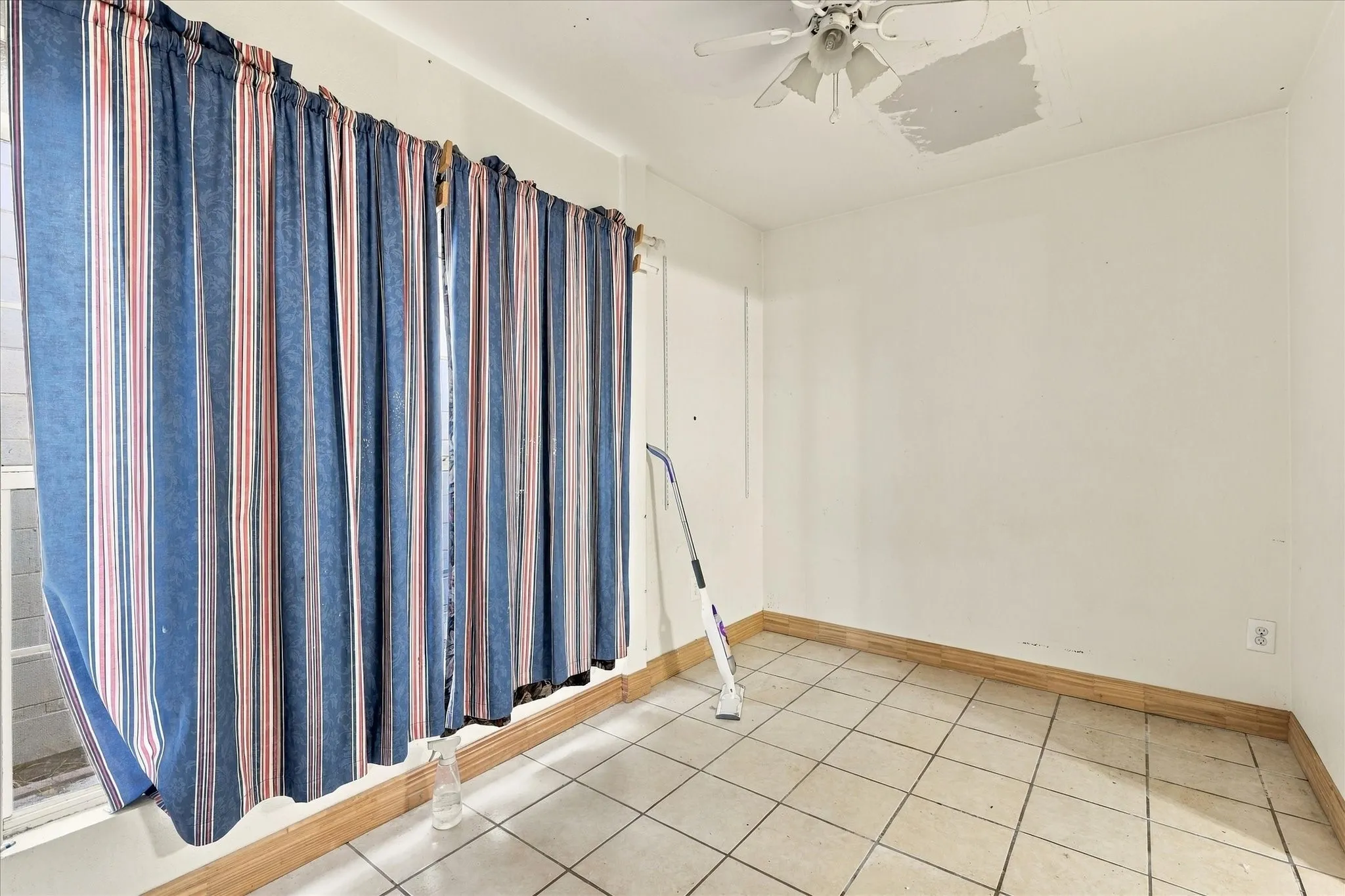 Room featuring white walls, tile flooring, and a ceiling-mounted light fixture